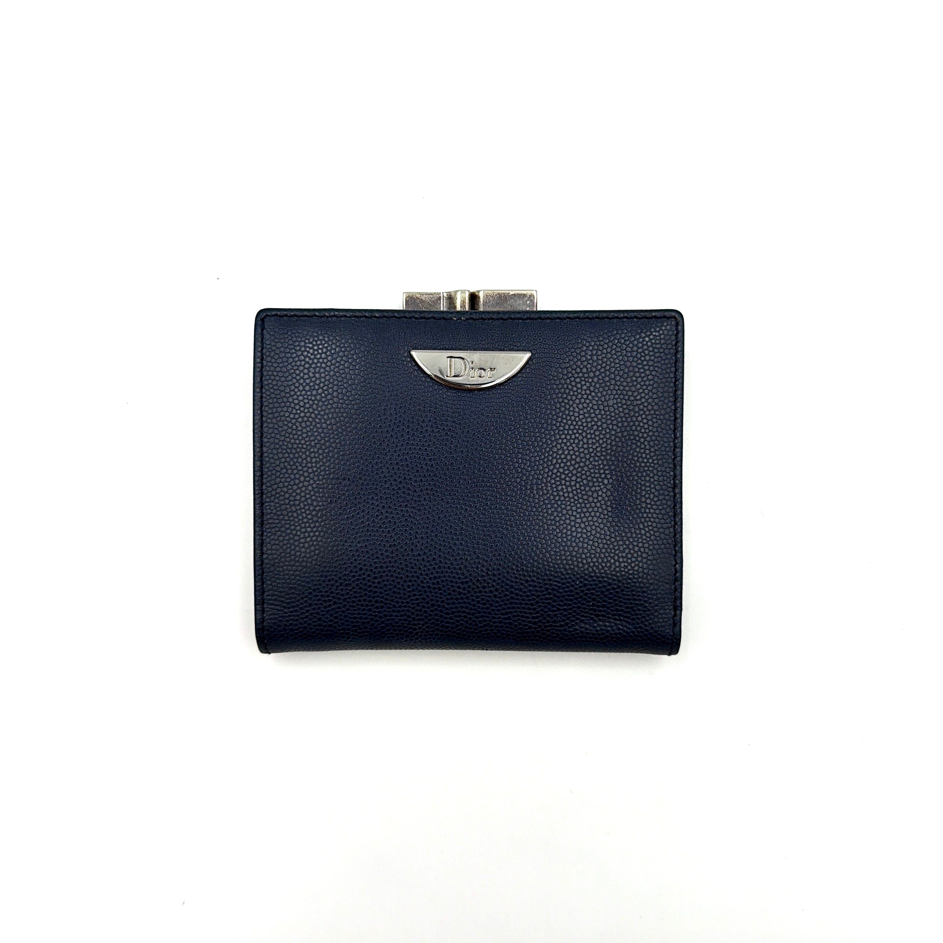 Dior compact navy blue leather wallet with silver-tone logo plaque and kiss-lock clasp, showcased against a clean background.