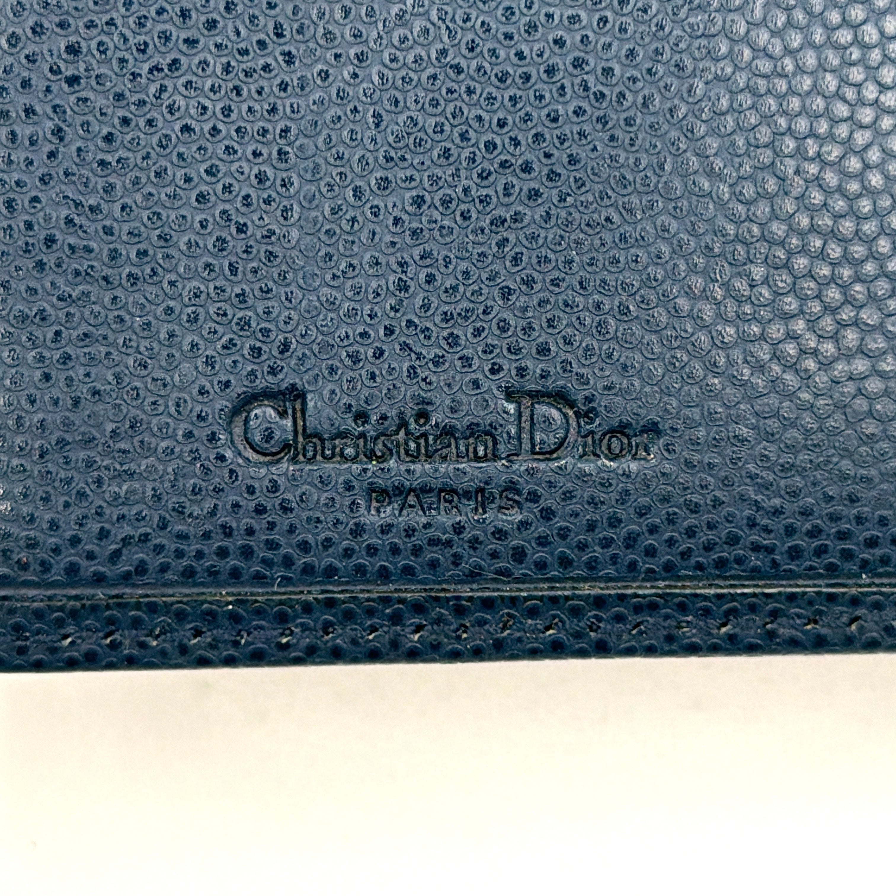Dior compact navy blue leather wallet with silver-tone logo plaque and kiss-lock clasp, showcased against a clean background.