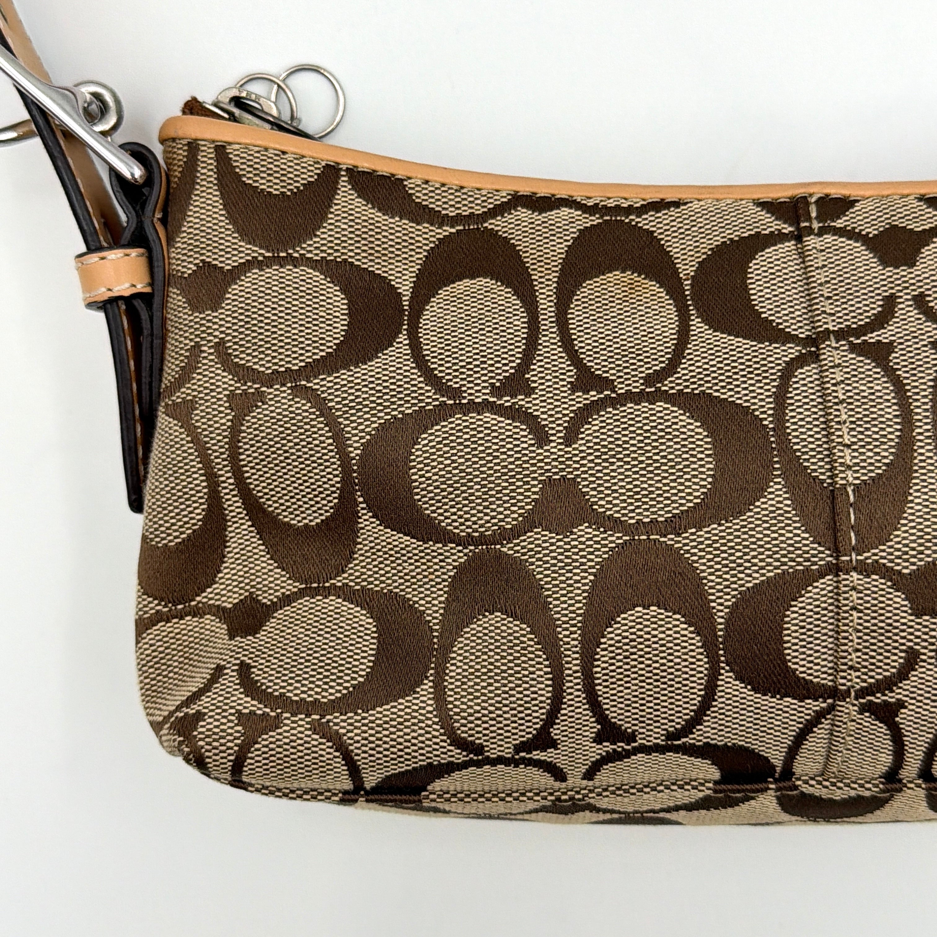 Coach Hamptons Demi Baguette shoulder bag in beige monogram canvas with tan leather trim and silver hardware.