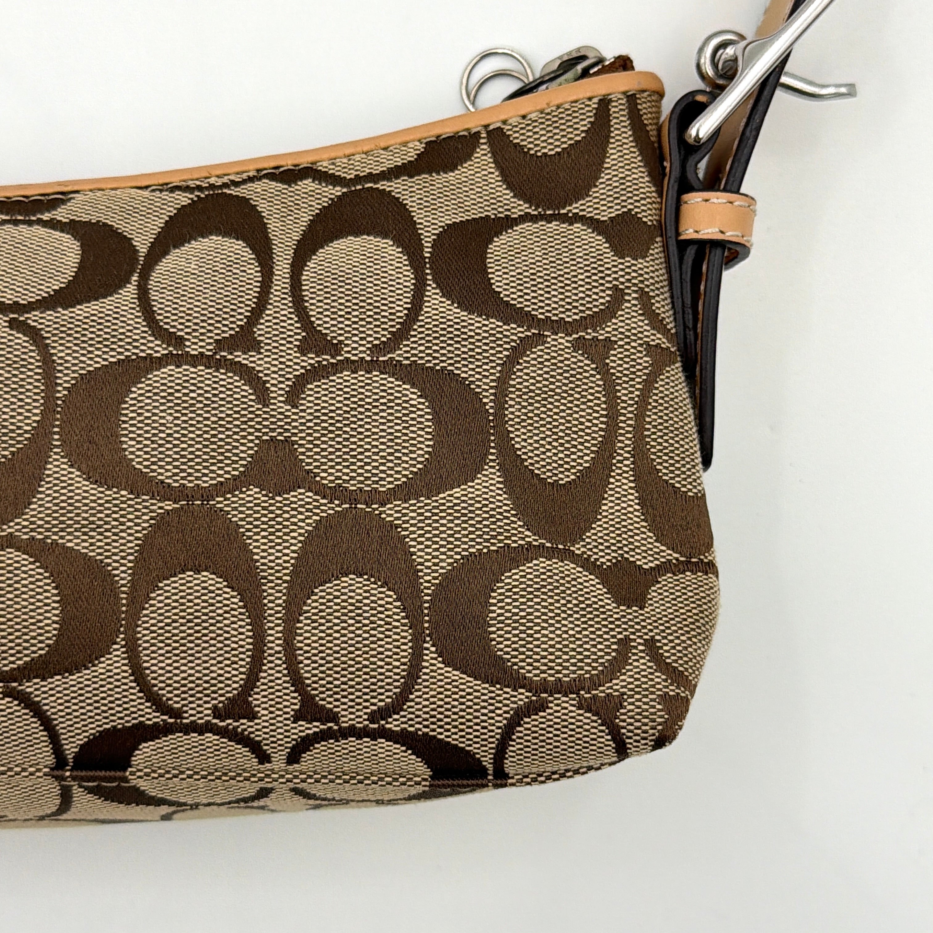 Coach Hamptons Demi Baguette shoulder bag in beige monogram canvas with tan leather trim and silver hardware.