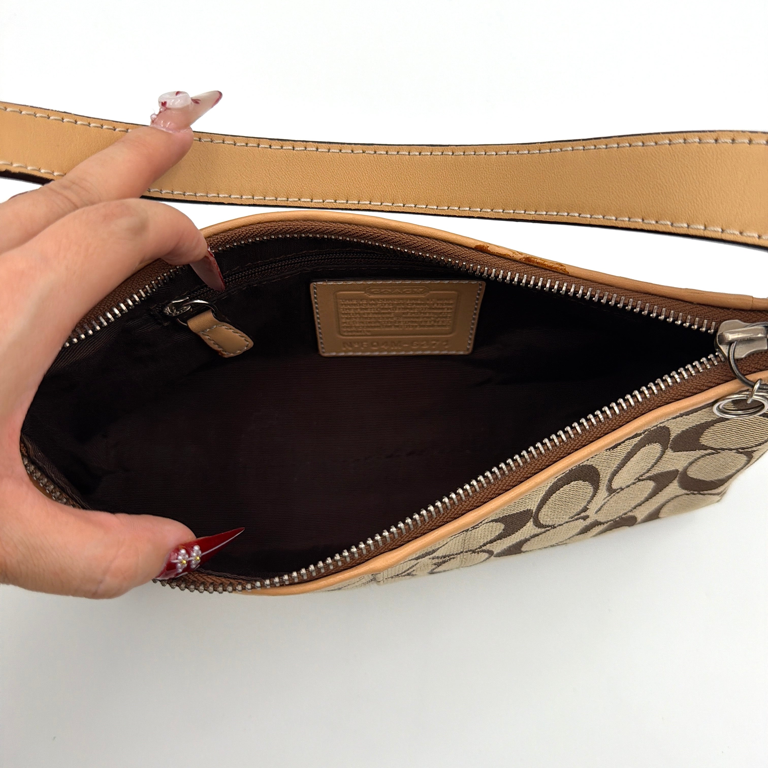 Coach Hamptons Demi Baguette shoulder bag in beige monogram canvas with tan leather trim and silver hardware.