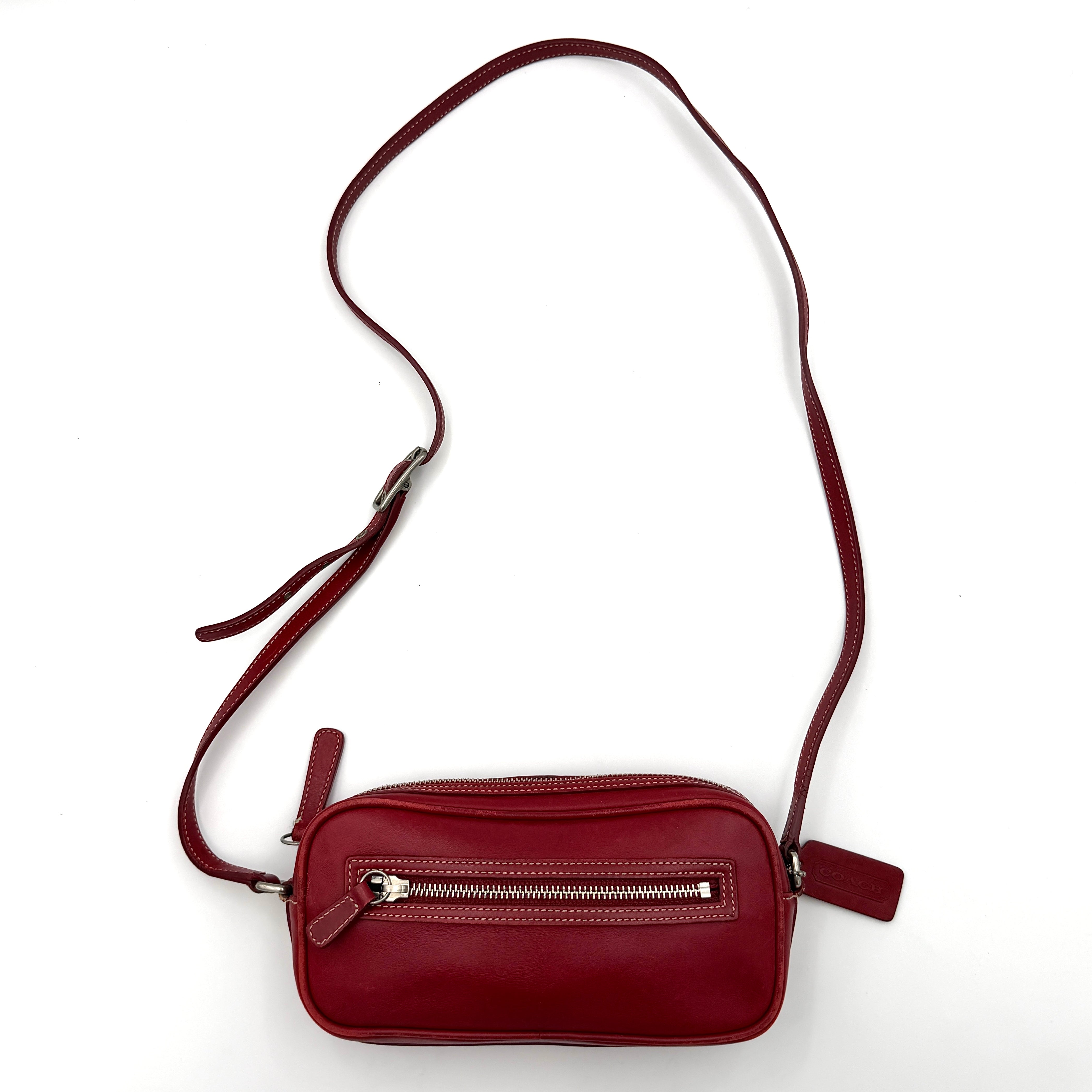Burgundy Coach Legacy West Crossbody Camera Bag with contrast stitching, exterior zip pocket, and slender adjustable strap.