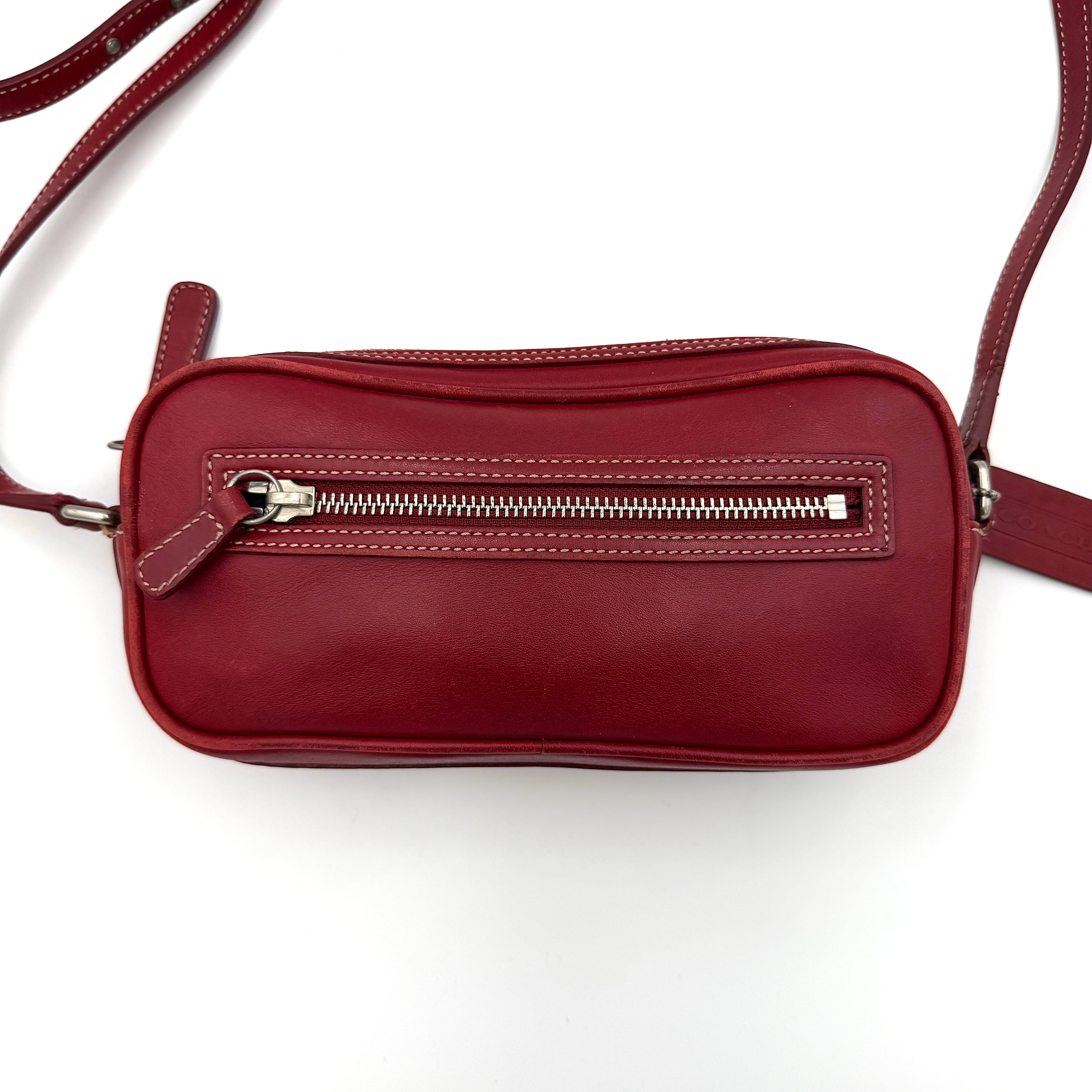 Burgundy Coach Legacy West Crossbody Camera Bag with contrast stitching, exterior zip pocket, and slender adjustable strap.