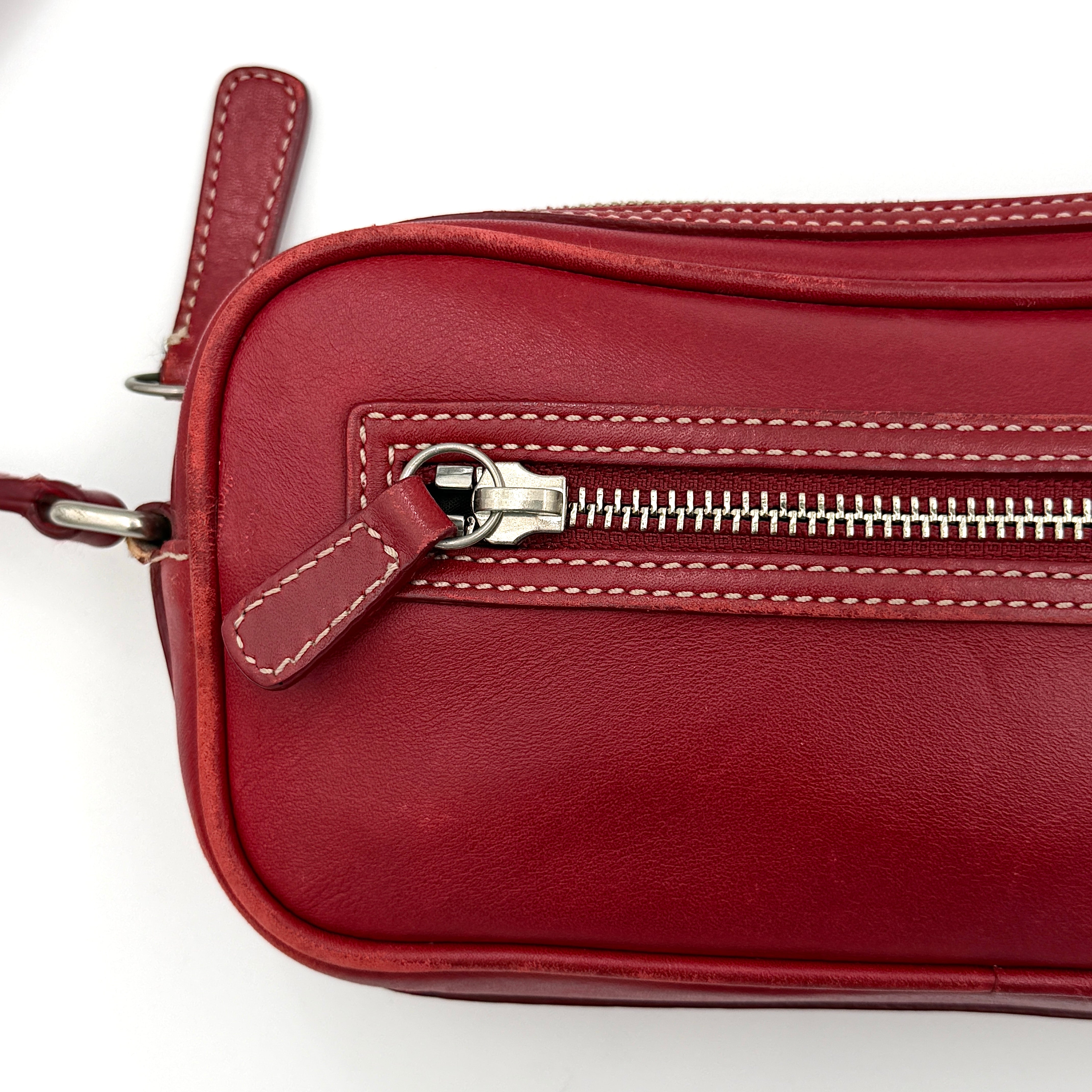 Burgundy Coach Legacy West Crossbody Camera Bag with contrast stitching, exterior zip pocket, and slender adjustable strap.