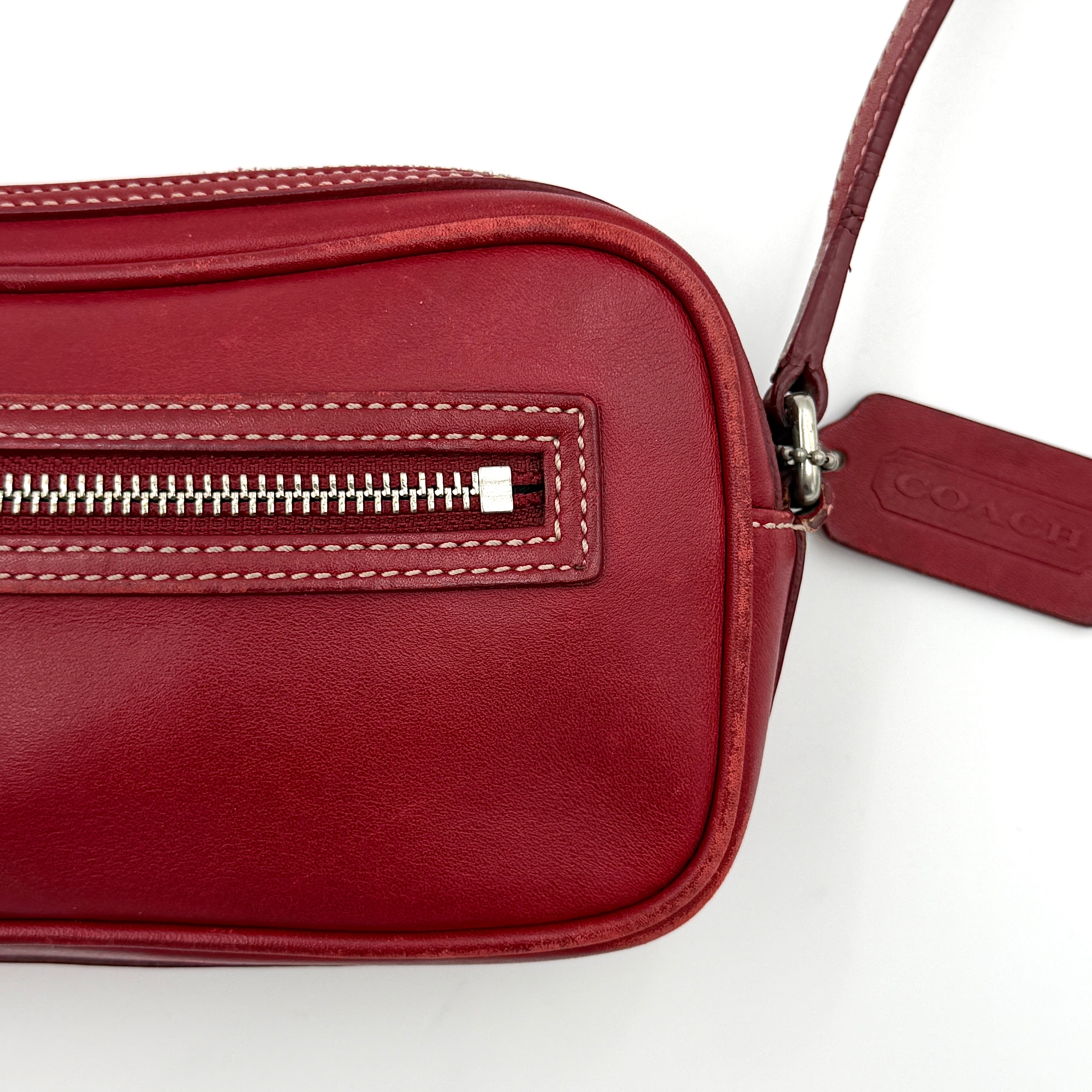 Burgundy Coach Legacy West Crossbody Camera Bag with contrast stitching, exterior zip pocket, and slender adjustable strap.
