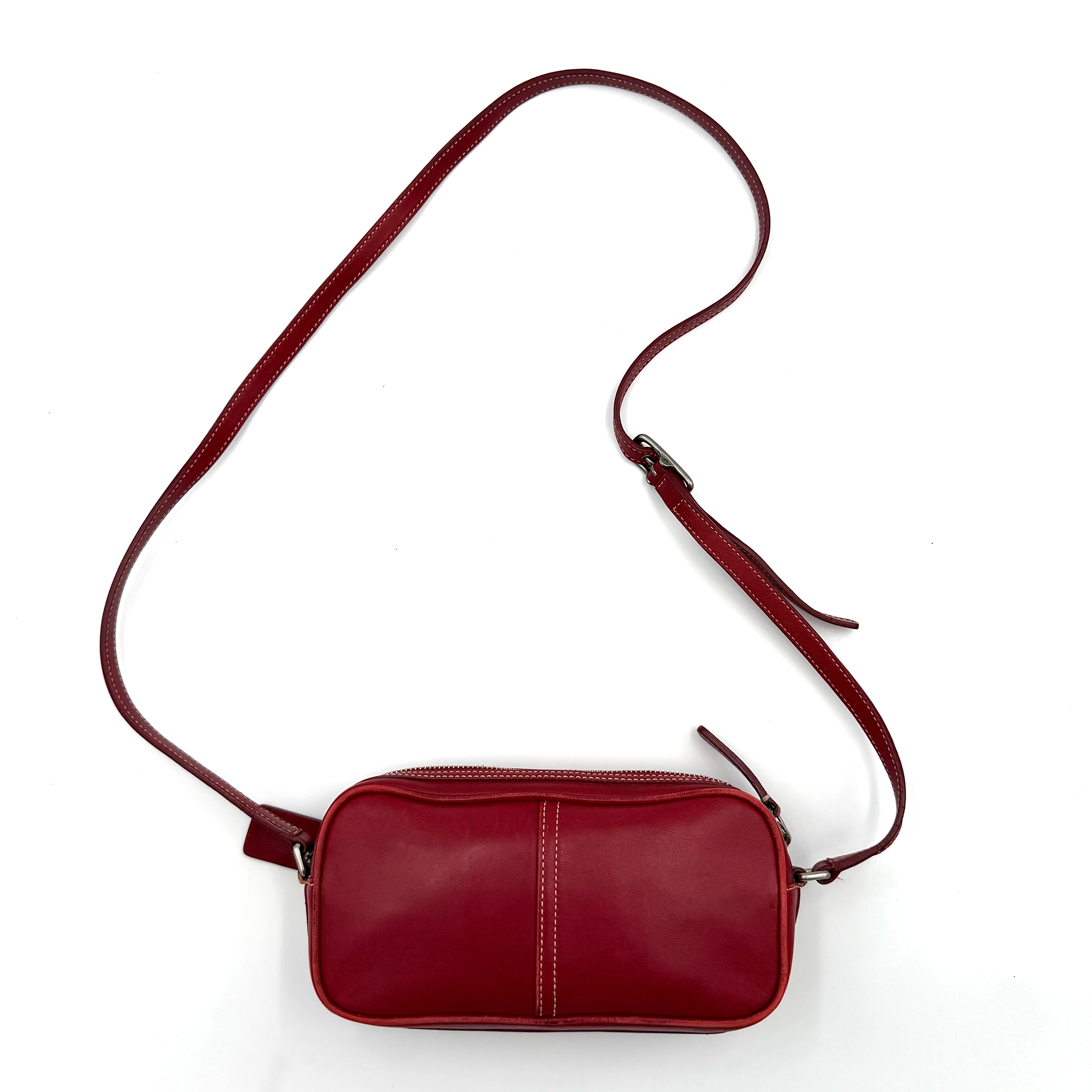 Burgundy Coach Legacy West Crossbody Camera Bag with contrast stitching, exterior zip pocket, and slender adjustable strap.