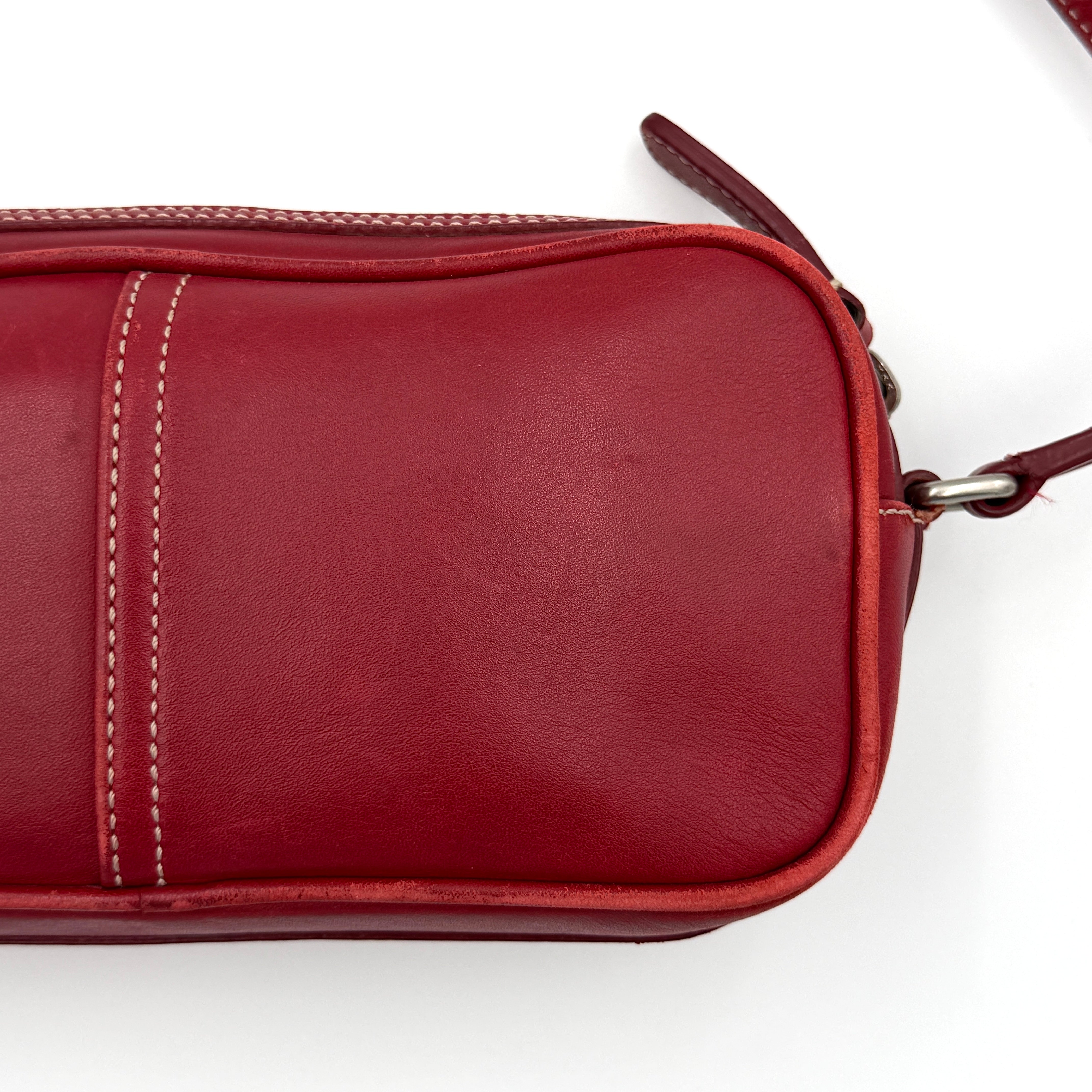 Burgundy Coach Legacy West Crossbody Camera Bag with contrast stitching, exterior zip pocket, and slender adjustable strap.