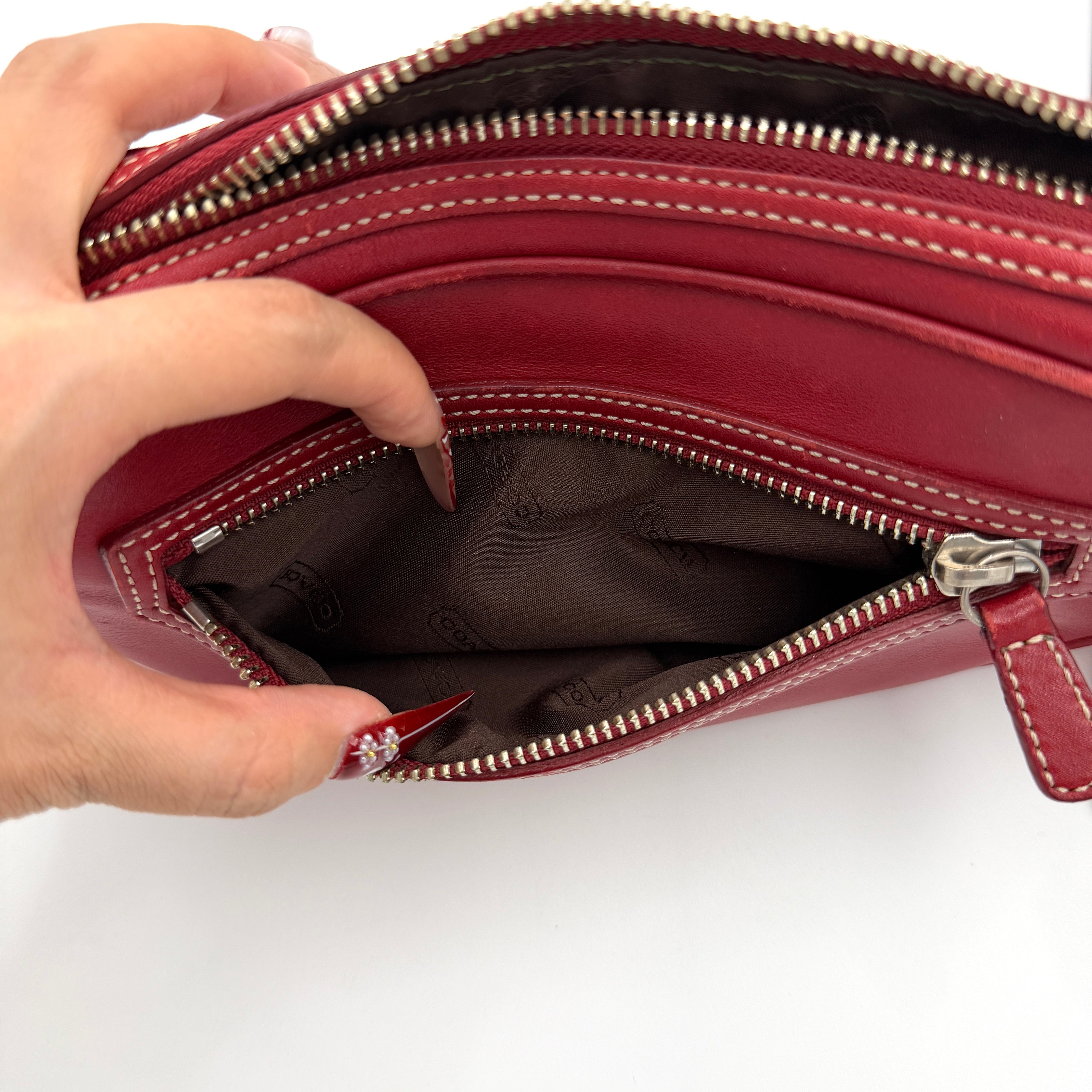 Burgundy Coach Legacy West Crossbody Camera Bag with contrast stitching, exterior zip pocket, and slender adjustable strap.