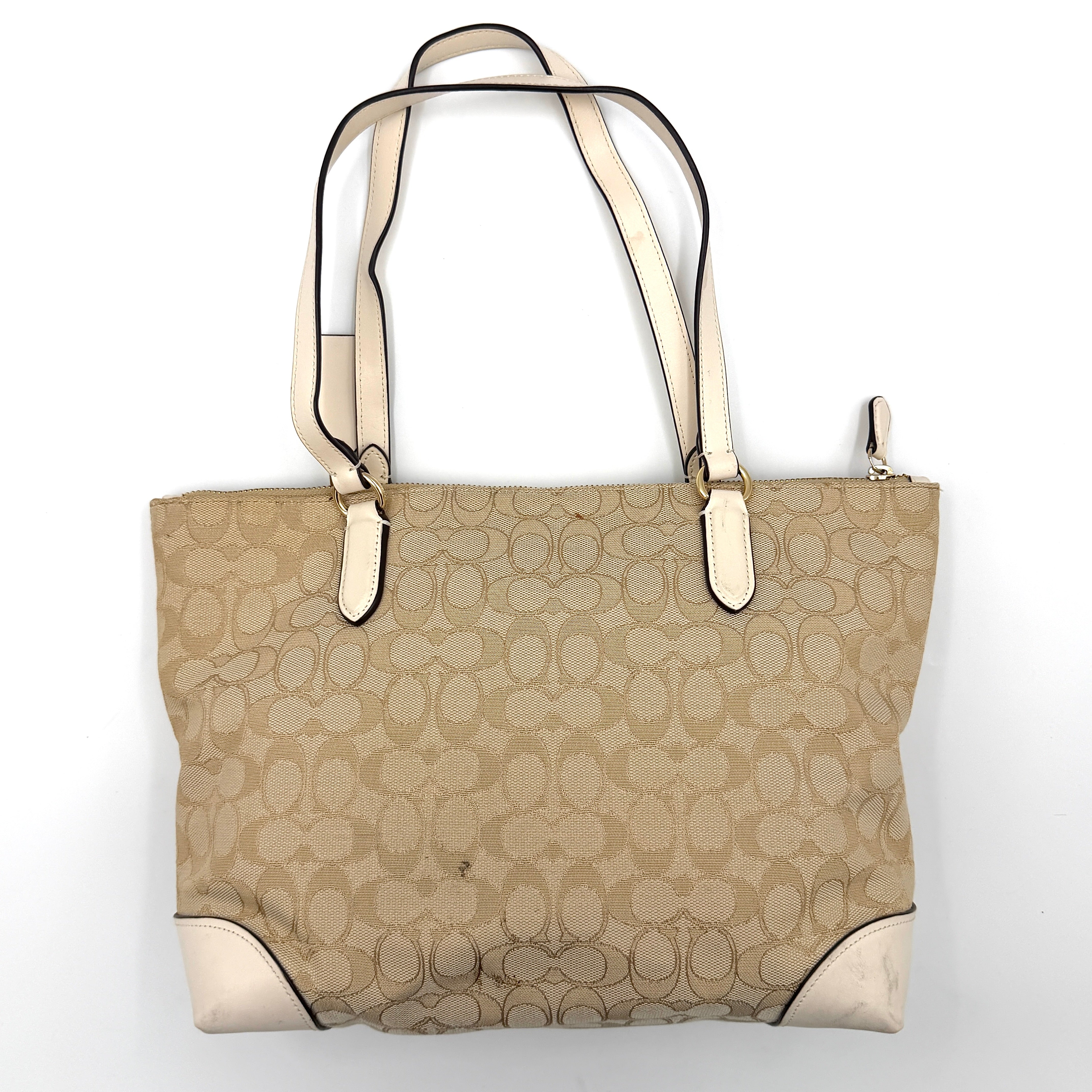 Coach Signature Zip Top Tote Bag in beige canvas with white leather trim and double handles, featuring the signature monogram print.