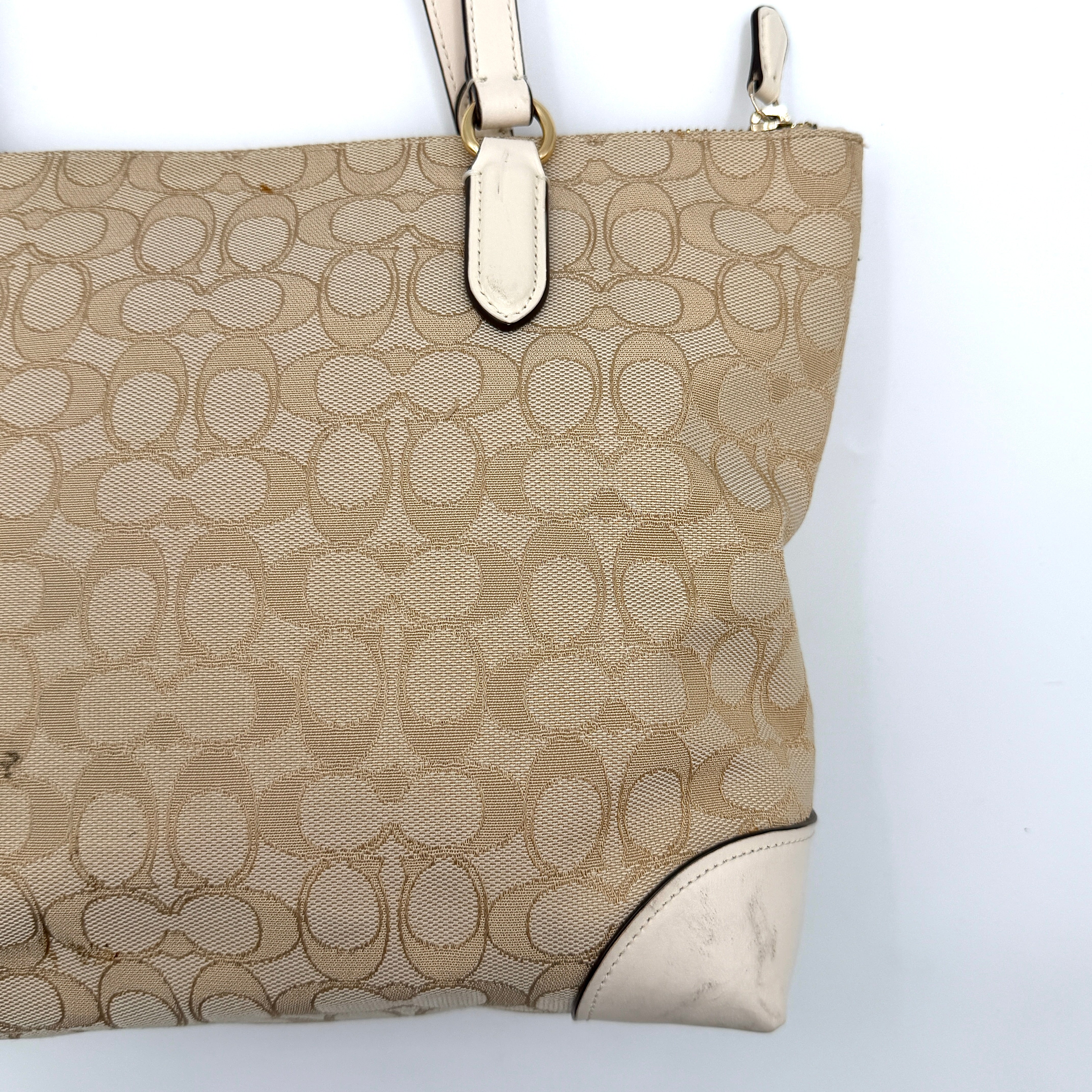 Coach Signature Zip Top Tote Bag in beige canvas with white leather trim and double handles, featuring the signature monogram print.