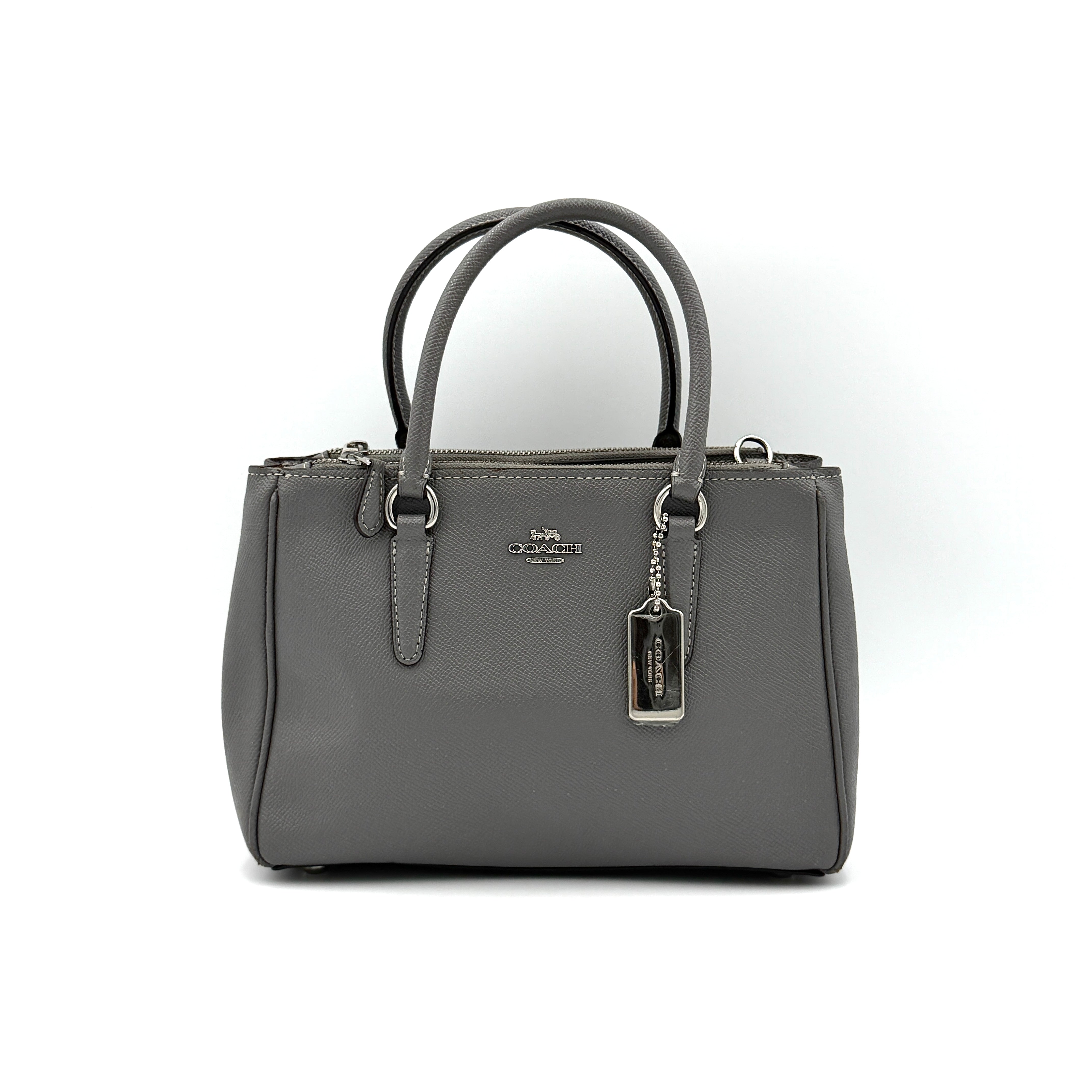 Coach 2Way Mini Surrey Carryall Handbag in grey textured leather with top handles and detachable strap, styled against a clean background.
