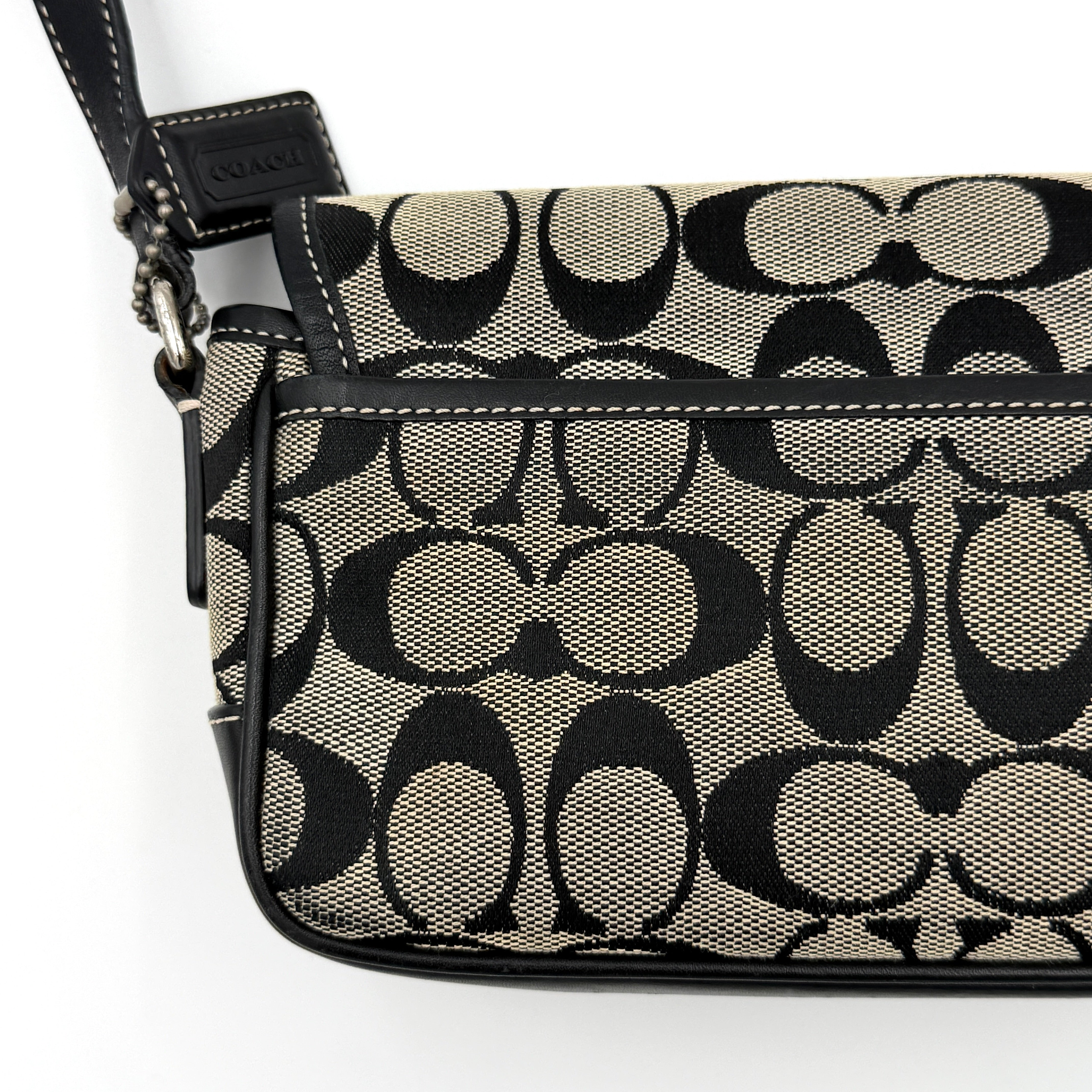 Coach Signature Double Buckle Crossbody bag in grey and black jacquard canvas, accented with black leather trim and dual silver-tone buckle detailing.