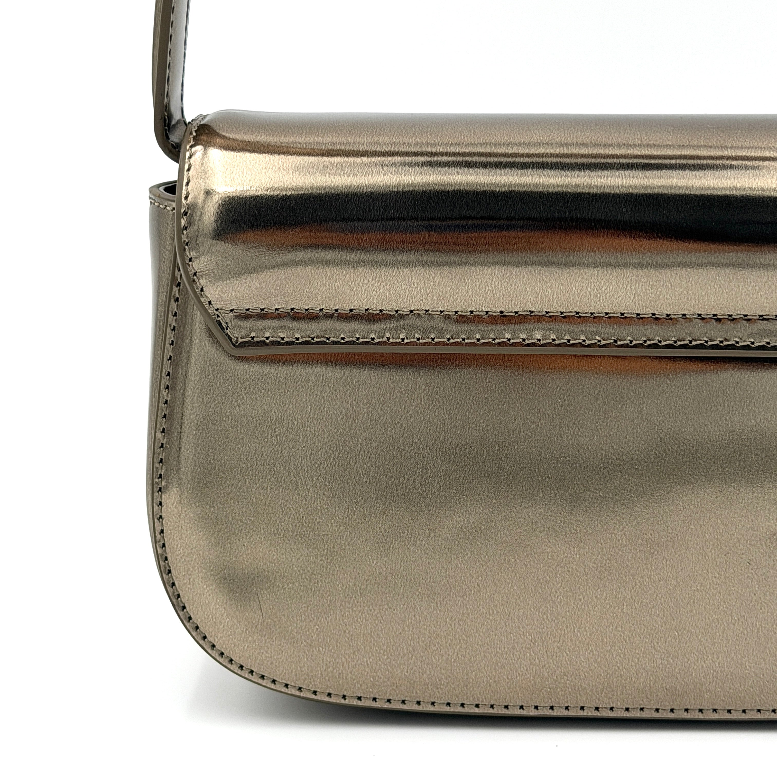 Diesel 1DR metallic silver shoulder bag with oversized chrome D-logo plaque, top handle, and detachable strap displayed against a white background.