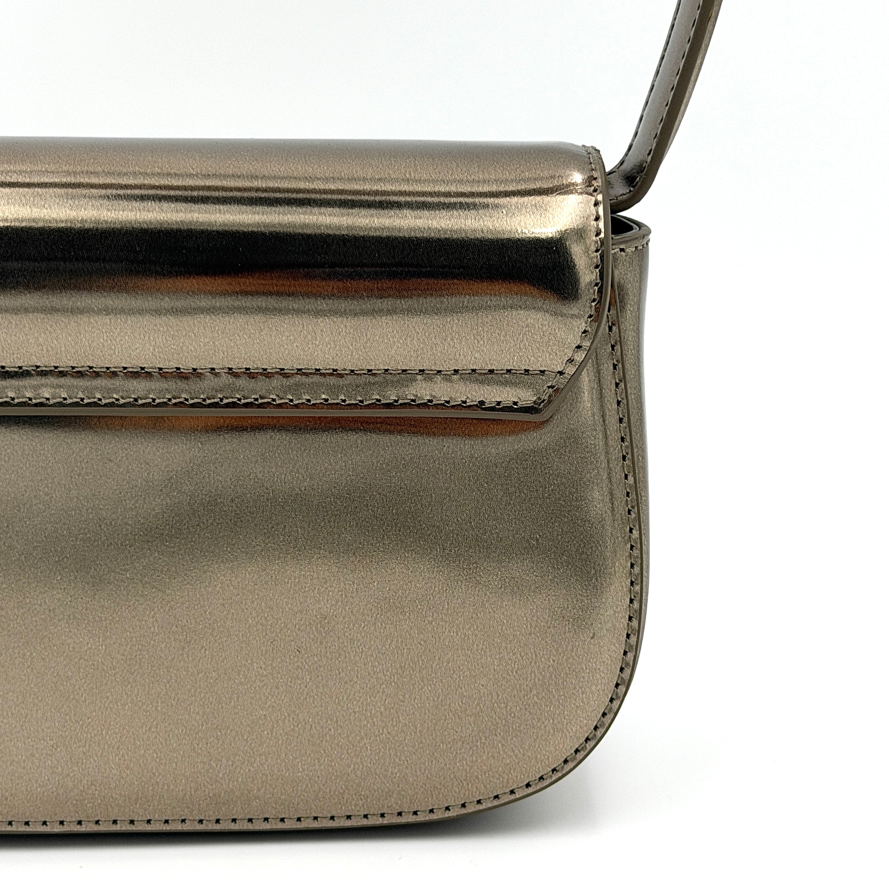 Diesel 1DR metallic silver shoulder bag with oversized chrome D-logo plaque, top handle, and detachable strap displayed against a white background.