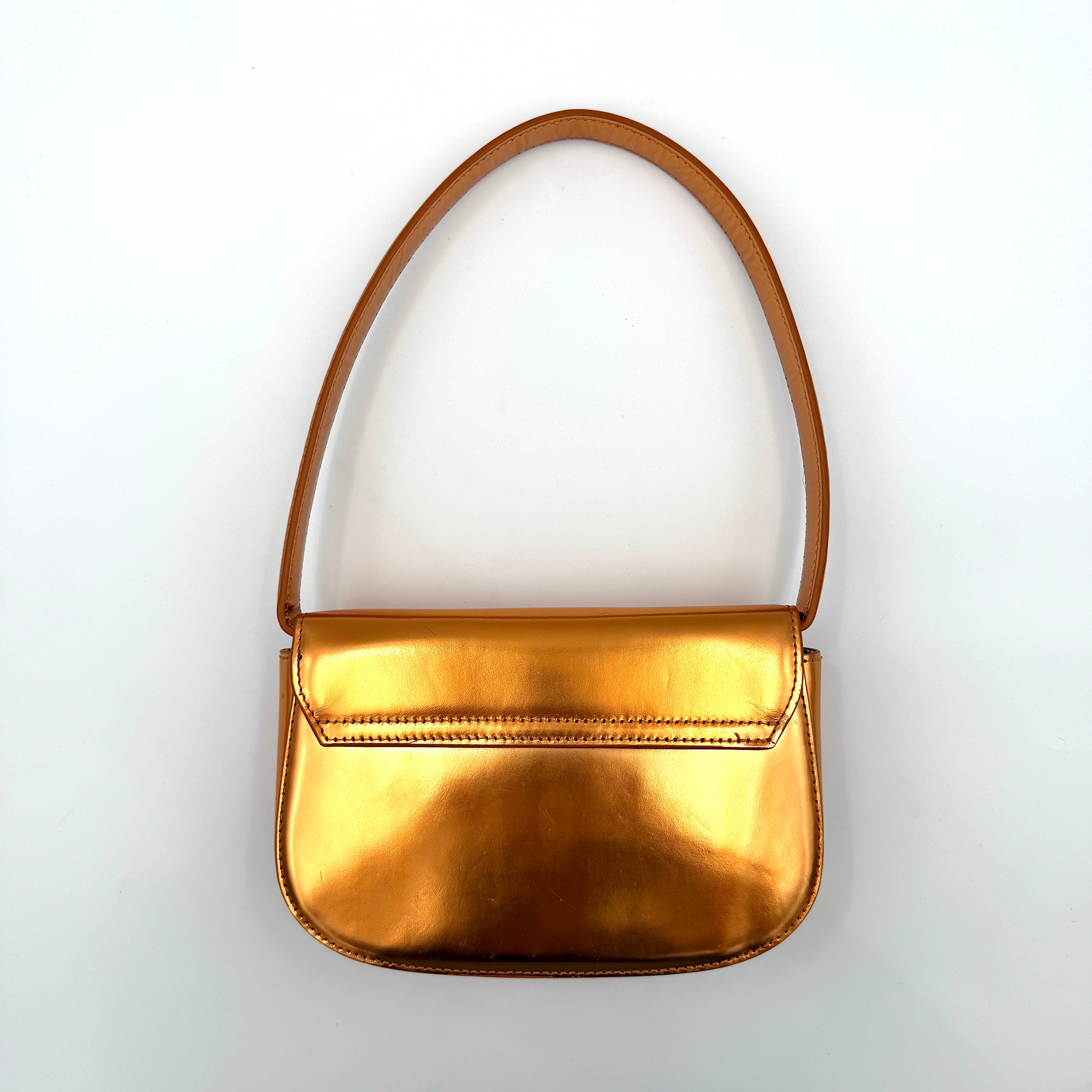 A Diesel 2Way 1DR Shoulder Bag in striking metallic gold with an embossed logo and detachable strap, displayed alongside its accessories.