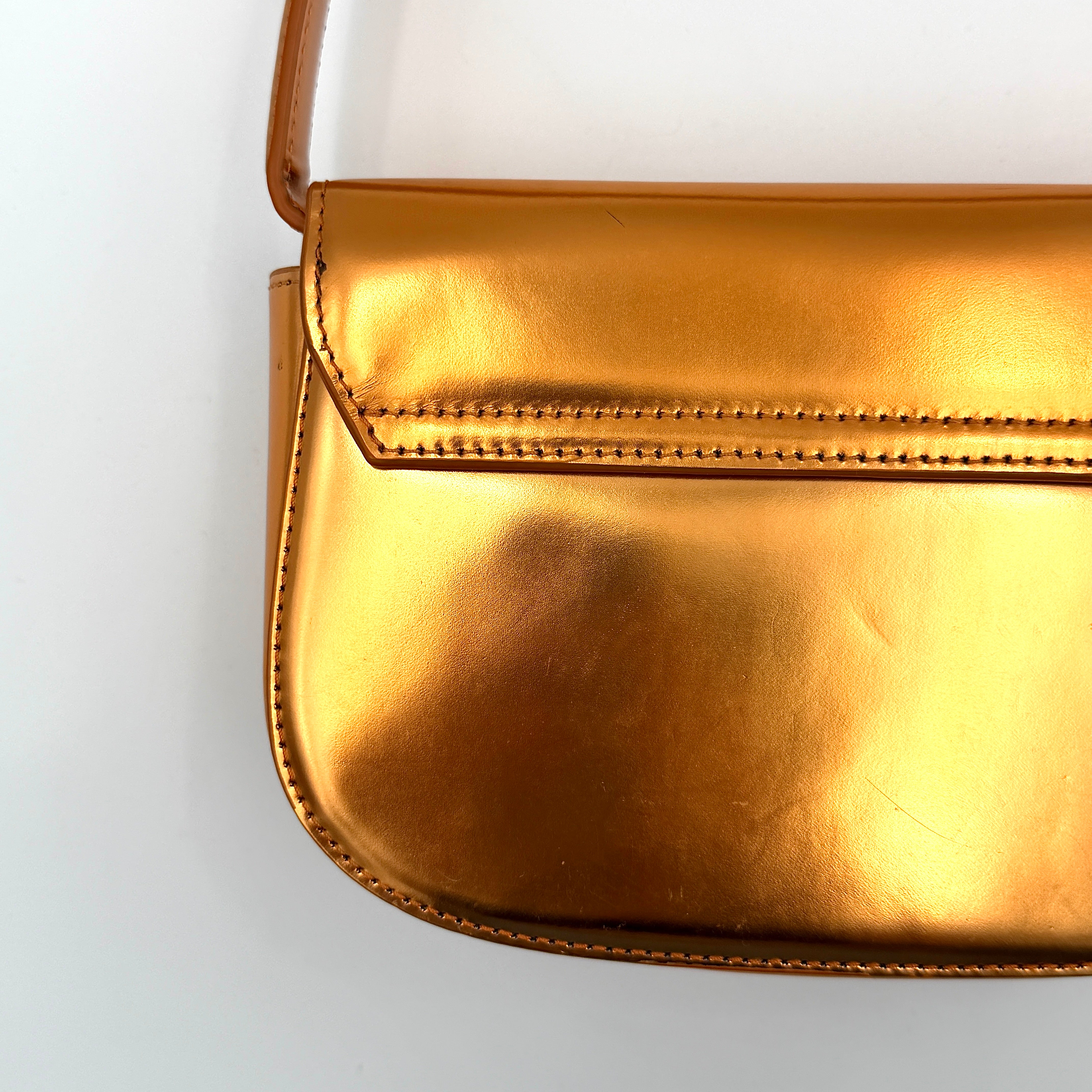 A Diesel 2Way 1DR Shoulder Bag in striking metallic gold with an embossed logo and detachable strap, displayed alongside its accessories.