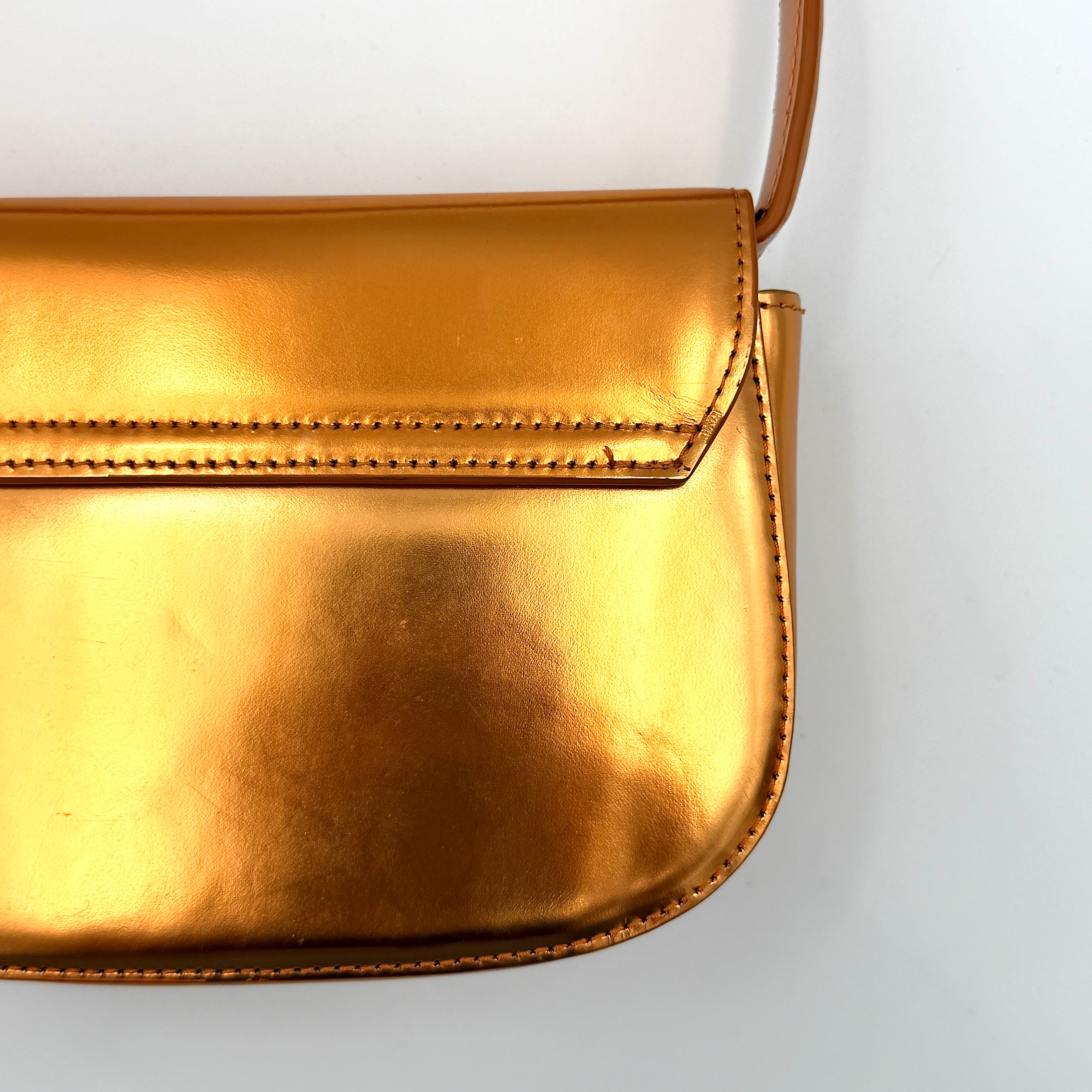 A Diesel 2Way 1DR Shoulder Bag in striking metallic gold with an embossed logo and detachable strap, displayed alongside its accessories.