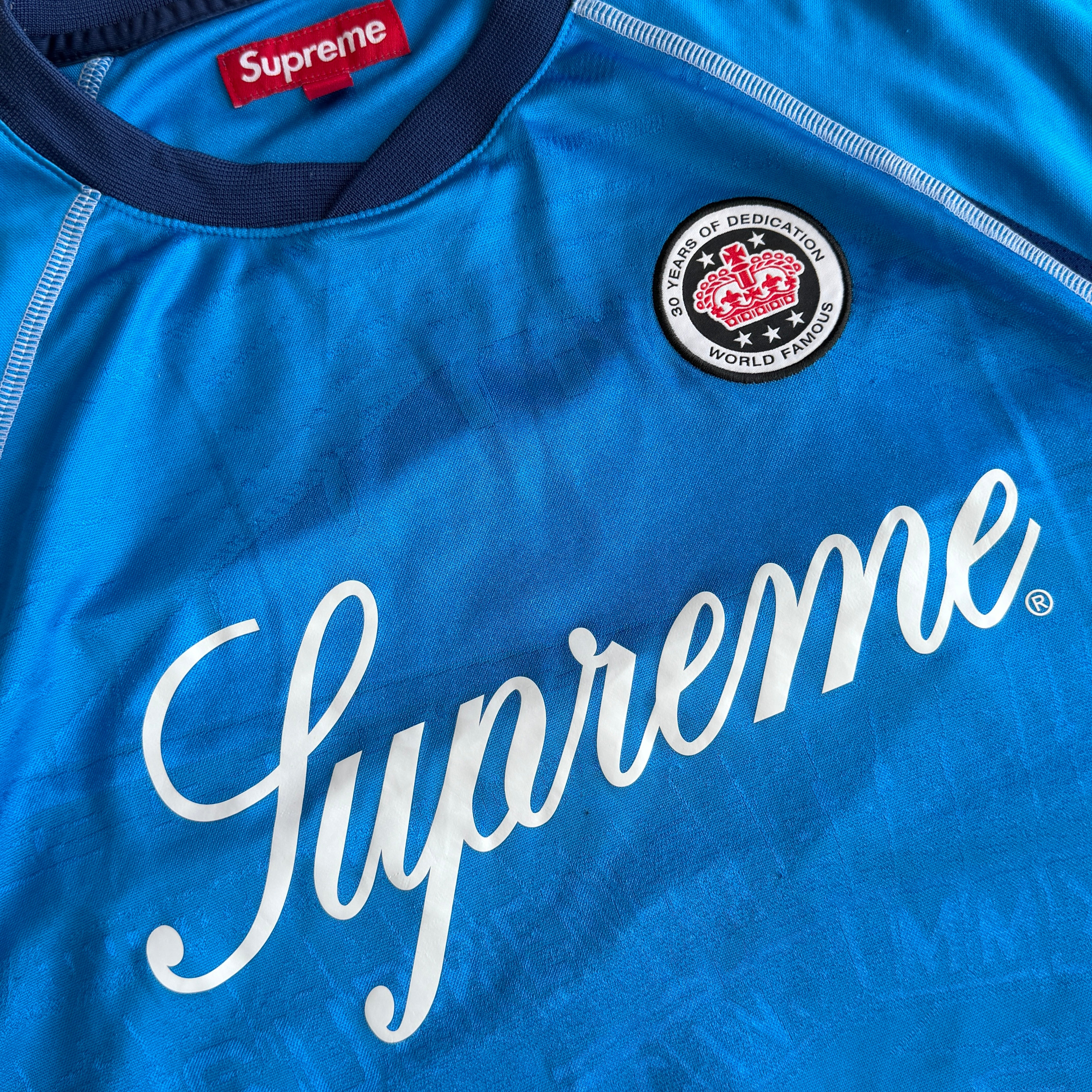Supreme Jacquard Soccer Jersey in blue with front Supreme script and patch, navy side panels, and sporty detailing.