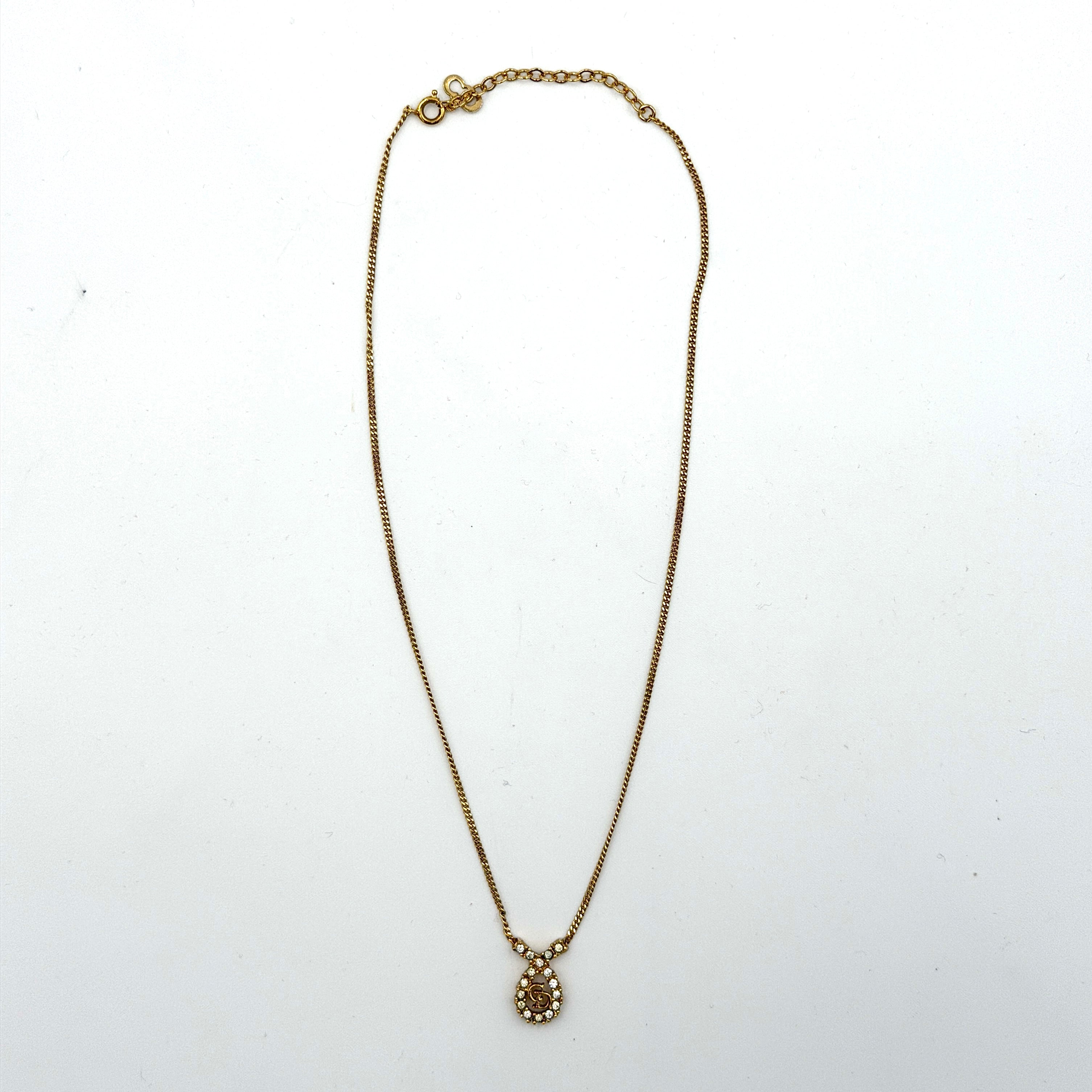 Dior CD Logo Rhinestone Necklace in gold featuring a teardrop pendant adorned with clear rhinestones and a gold chain.