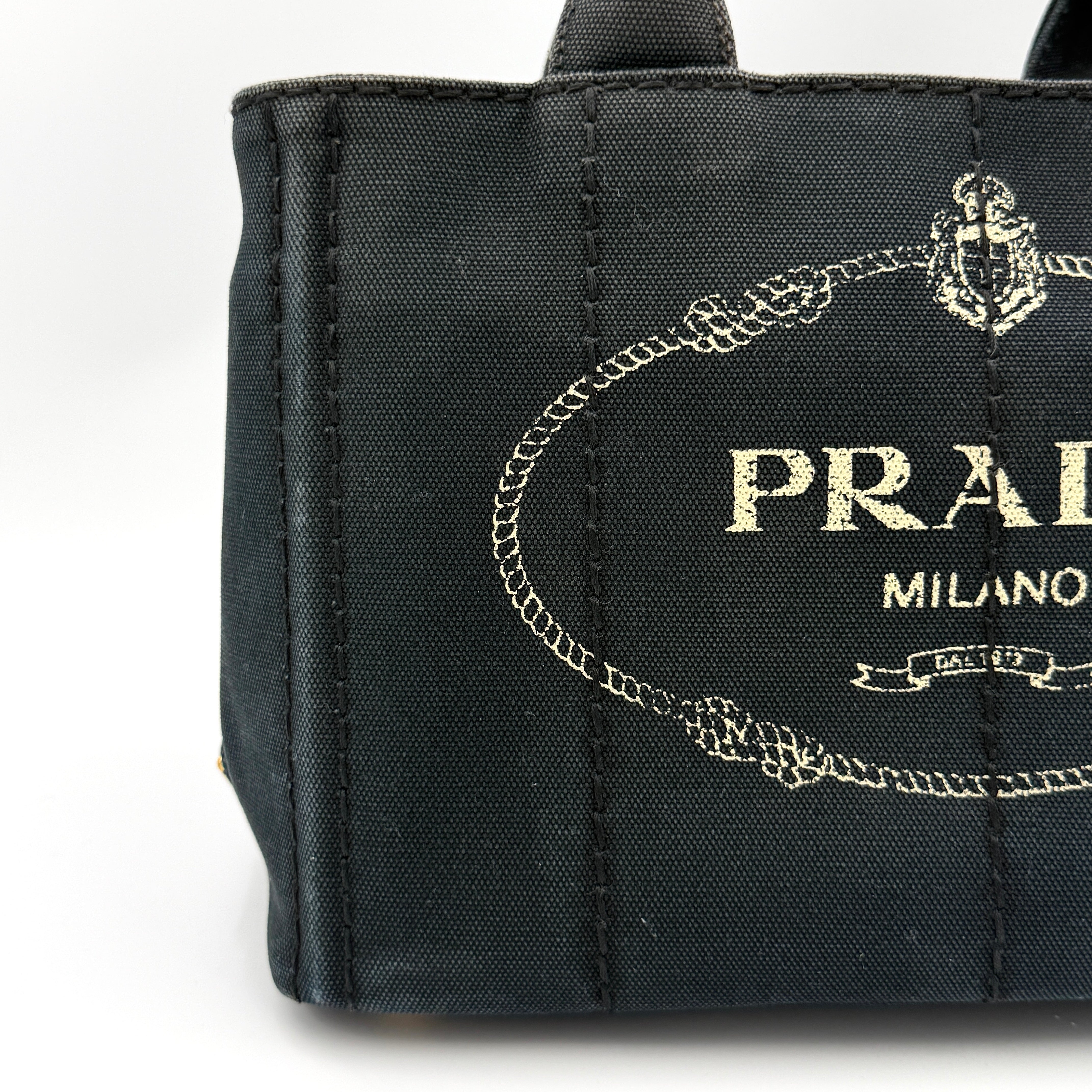 Front-facing Prada Canapa Embroidered Logo Tote in black canvas with ivory stitched logo and double handles.