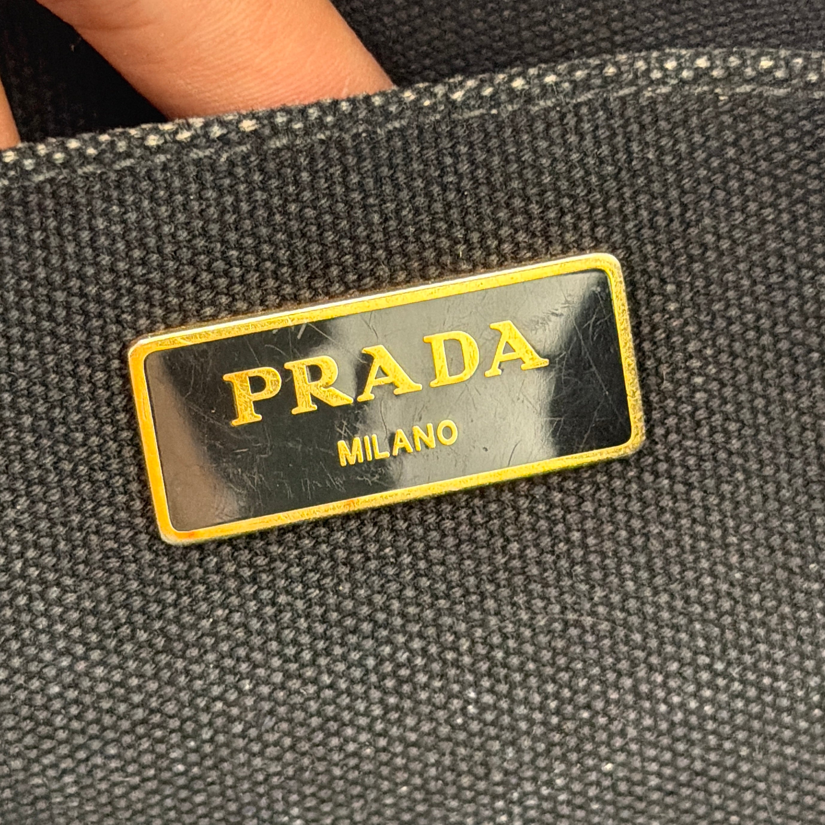 Front-facing Prada Canapa Embroidered Logo Tote in black canvas with ivory stitched logo and double handles.