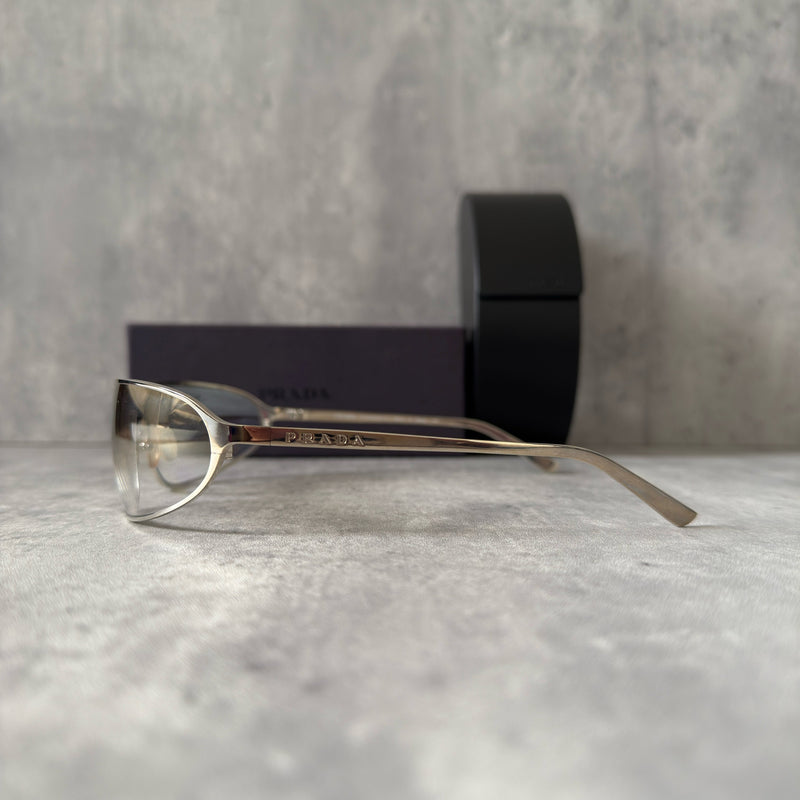 Prada Transparent Silver Vintage Sunglasses with a sleek titanium frame and clear gradient lenses, featuring an engraved Prada logo on the temples.