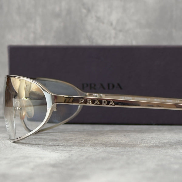 Prada Transparent Silver Vintage Sunglasses with a sleek titanium frame and clear gradient lenses, featuring an engraved Prada logo on the temples.