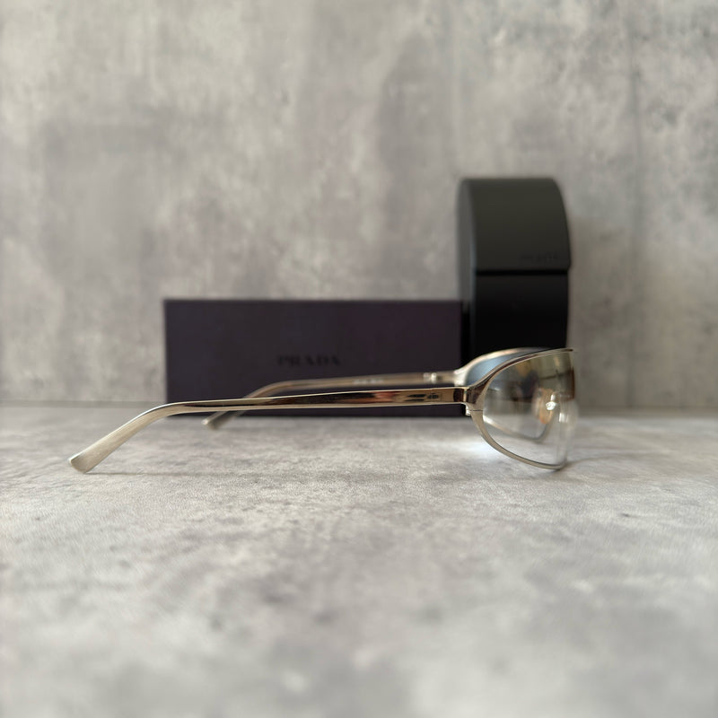 Prada Transparent Silver Vintage Sunglasses with a sleek titanium frame and clear gradient lenses, featuring an engraved Prada logo on the temples.