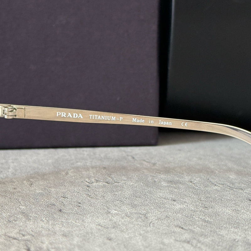 Prada Transparent Silver Vintage Sunglasses with a sleek titanium frame and clear gradient lenses, featuring an engraved Prada logo on the temples.