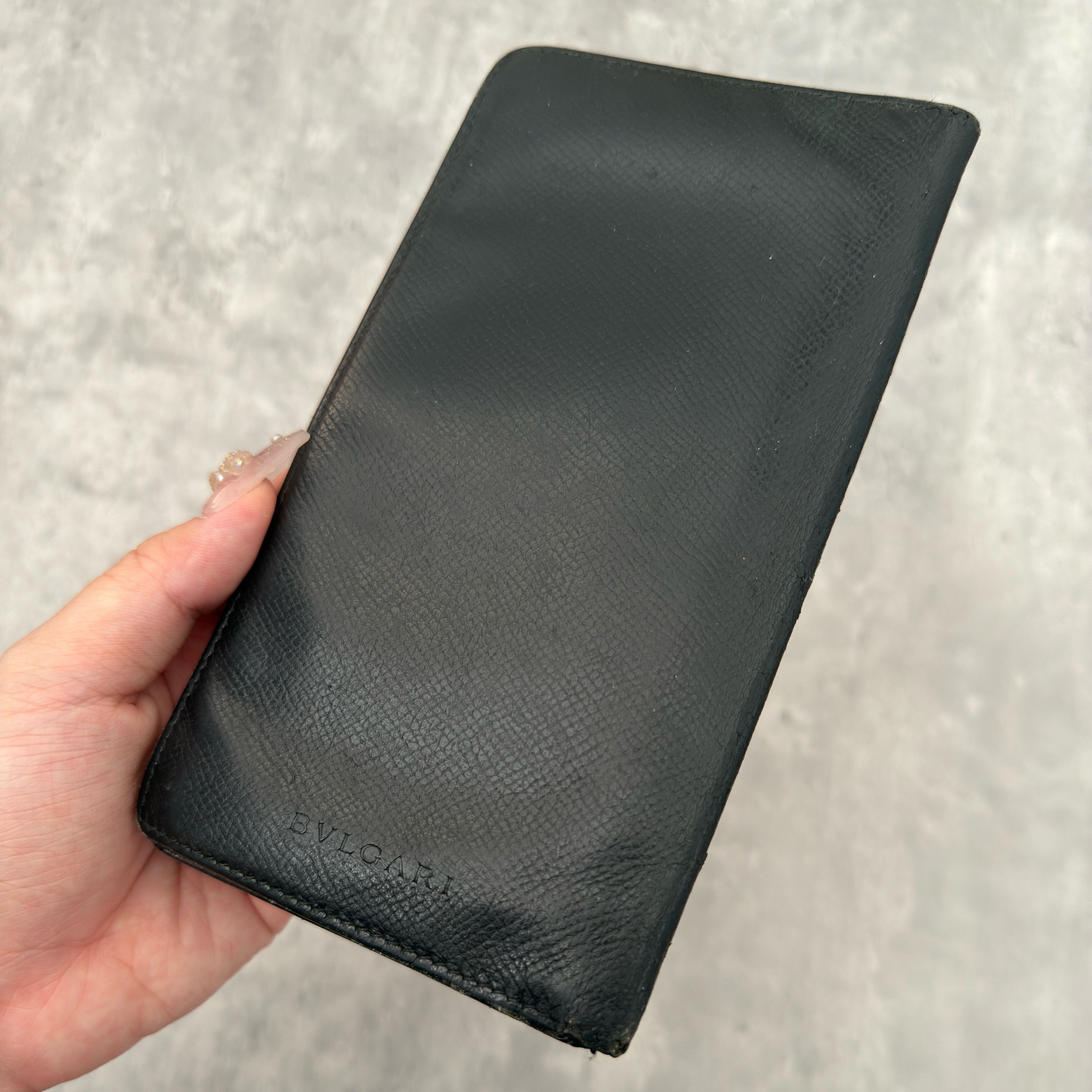 Bvlgari Bi-Fold Leather Black Long Wallet, crafted from textured black leather with multiple card slots and bill compartments for organization.