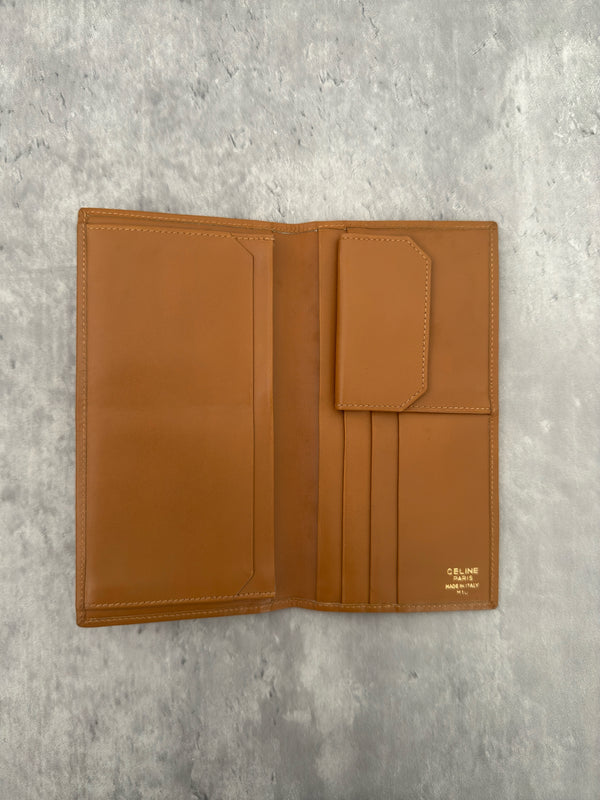 Celine Macadam Triomphe Canvas Long Wallet in brown monogram canvas with tan leather trim, featuring a bifold design with multiple compartments and a snap-button coin pocket.