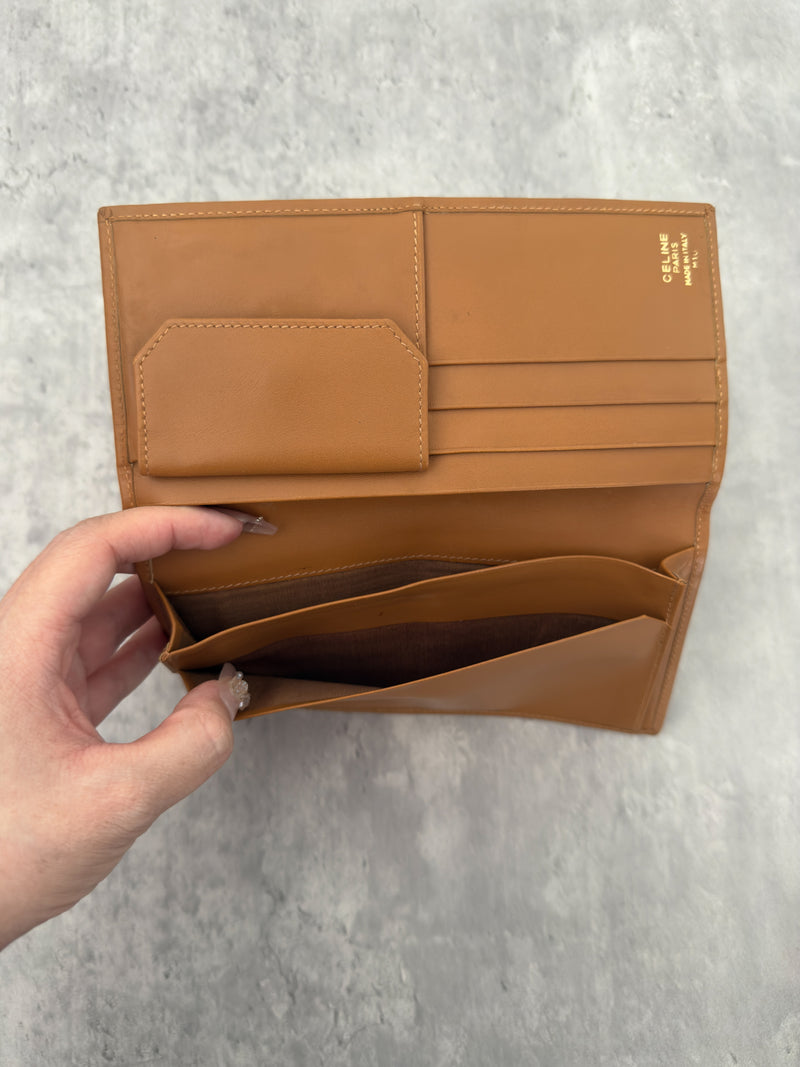 Celine Macadam Triomphe Canvas Long Wallet in brown monogram canvas with tan leather trim, featuring a bifold design with multiple compartments and a snap-button coin pocket.