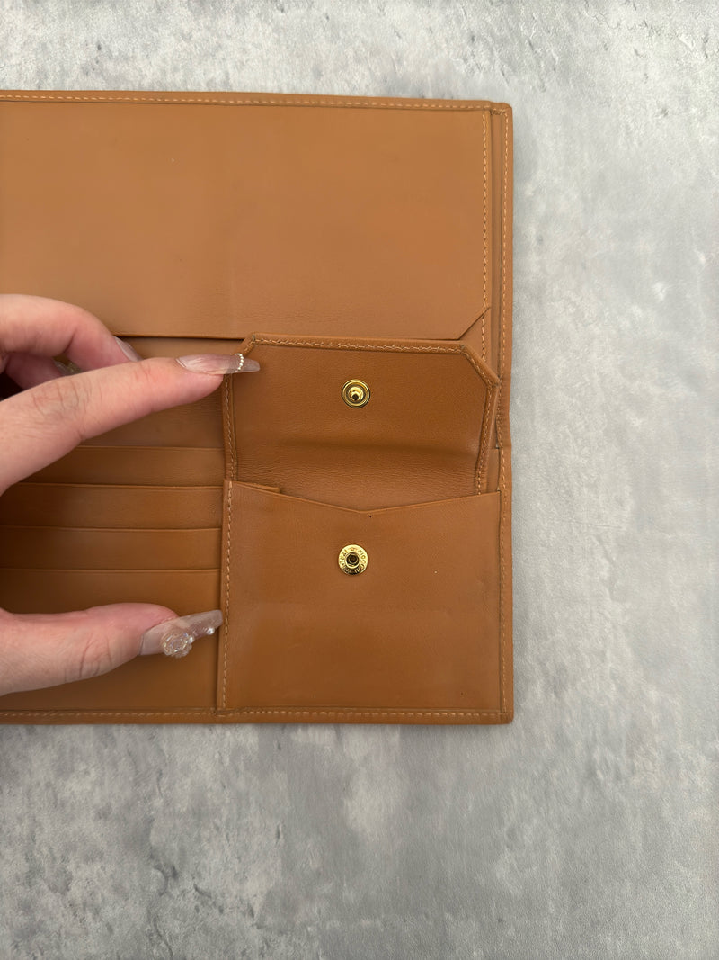 Celine Macadam Triomphe Canvas Long Wallet in brown monogram canvas with tan leather trim, featuring a bifold design with multiple compartments and a snap-button coin pocket.