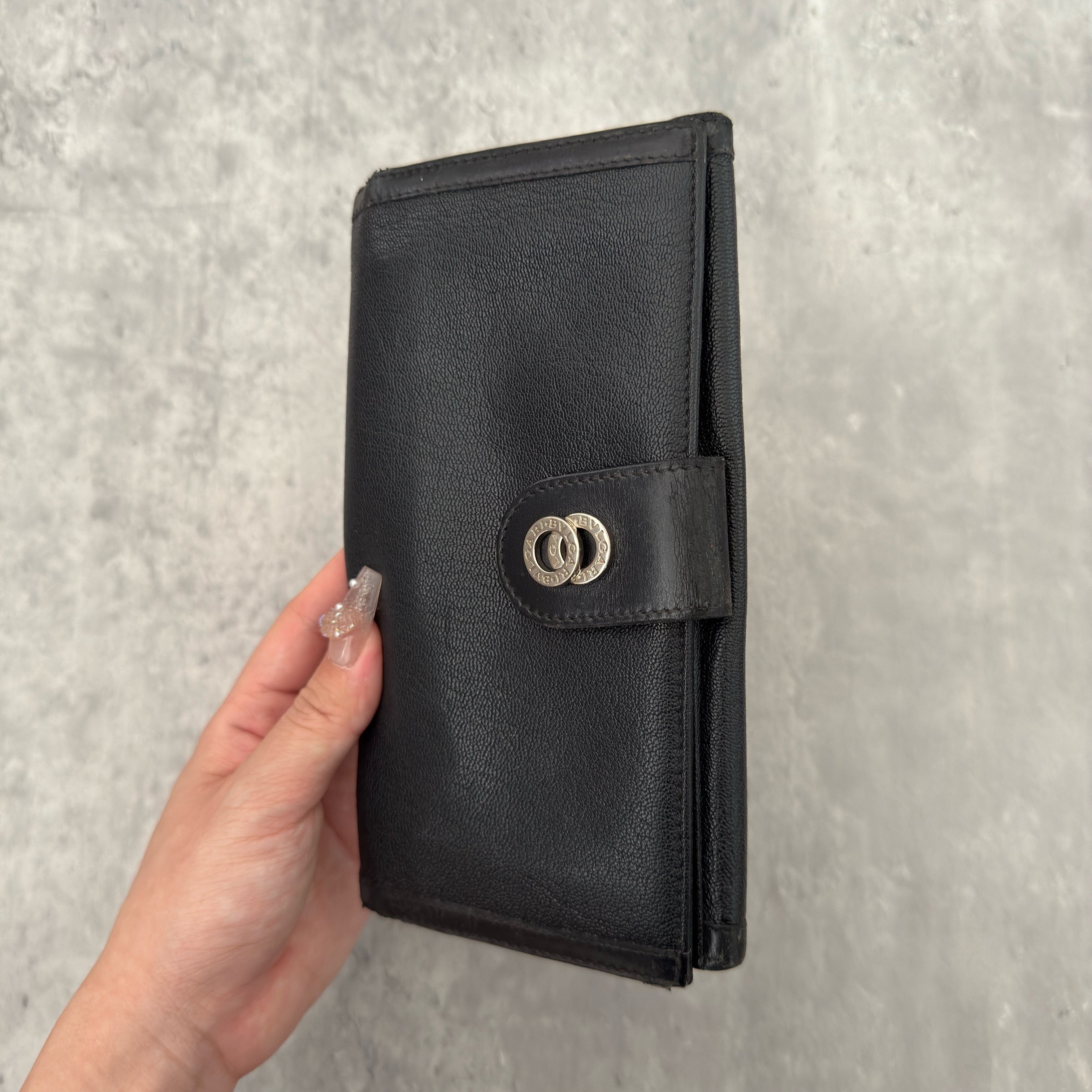 Bvlgari Doppio Tondo Bifold Long Wallet in black leather, featuring a silver-tone logo clasp, red fabric interior, and multiple compartments.