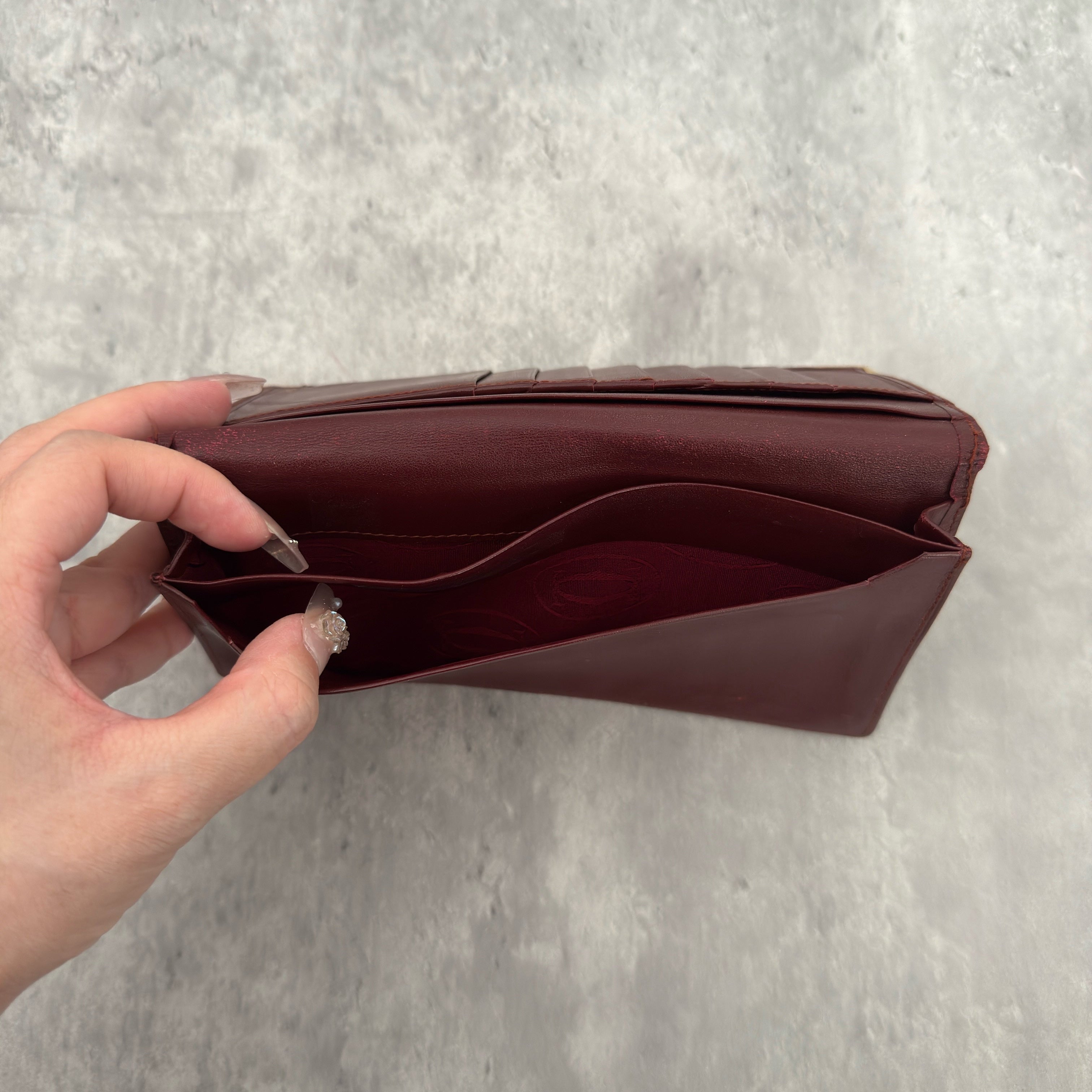 Cartier Must De Cartier Burgundy Long Wallet in burgundy leather with gold-tone corner accents and multiple compartments.