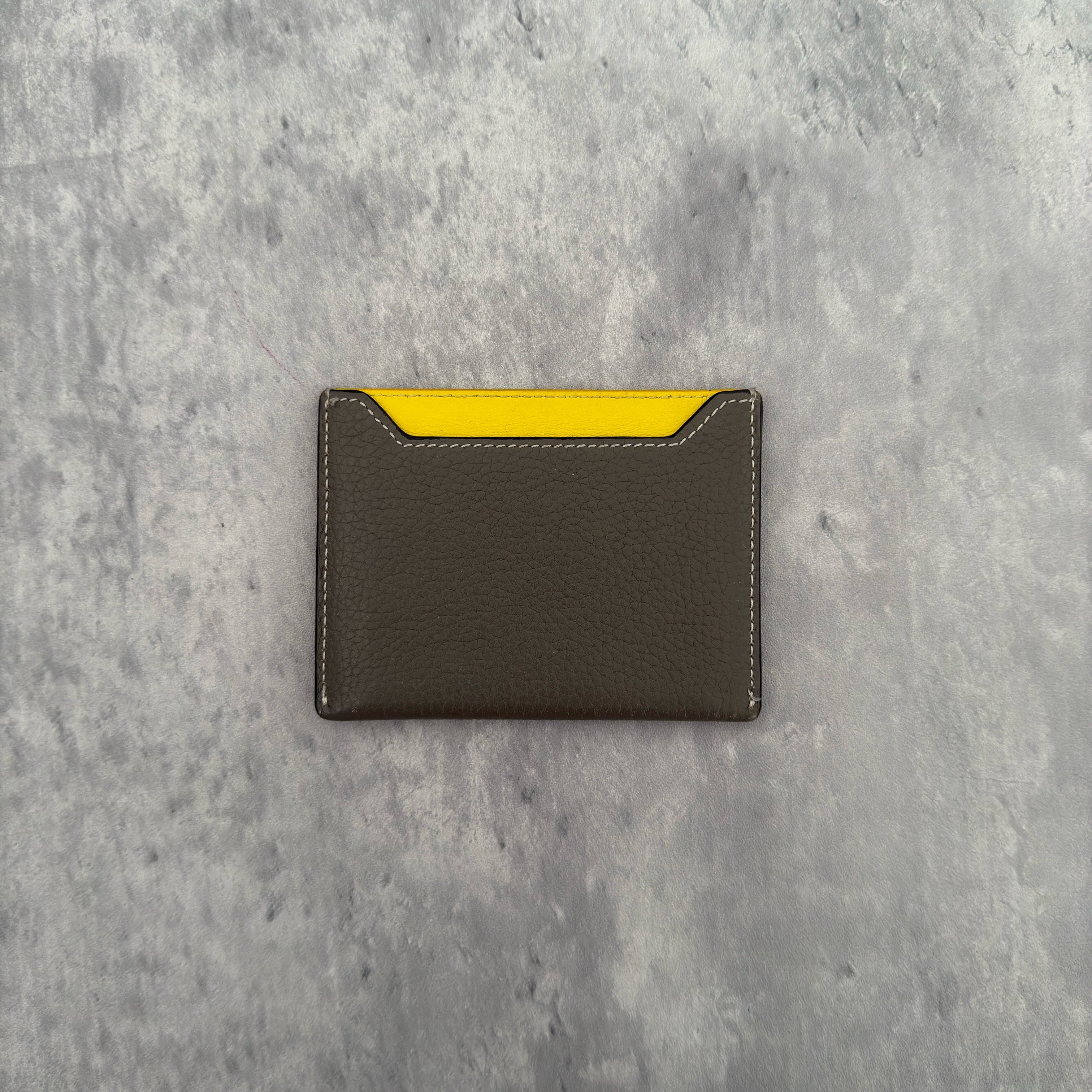 Celine Drummed Calfskin Bi-Color Cardholder in olive green and yellow, featuring a minimalist design with multiple card slots and central pocket.