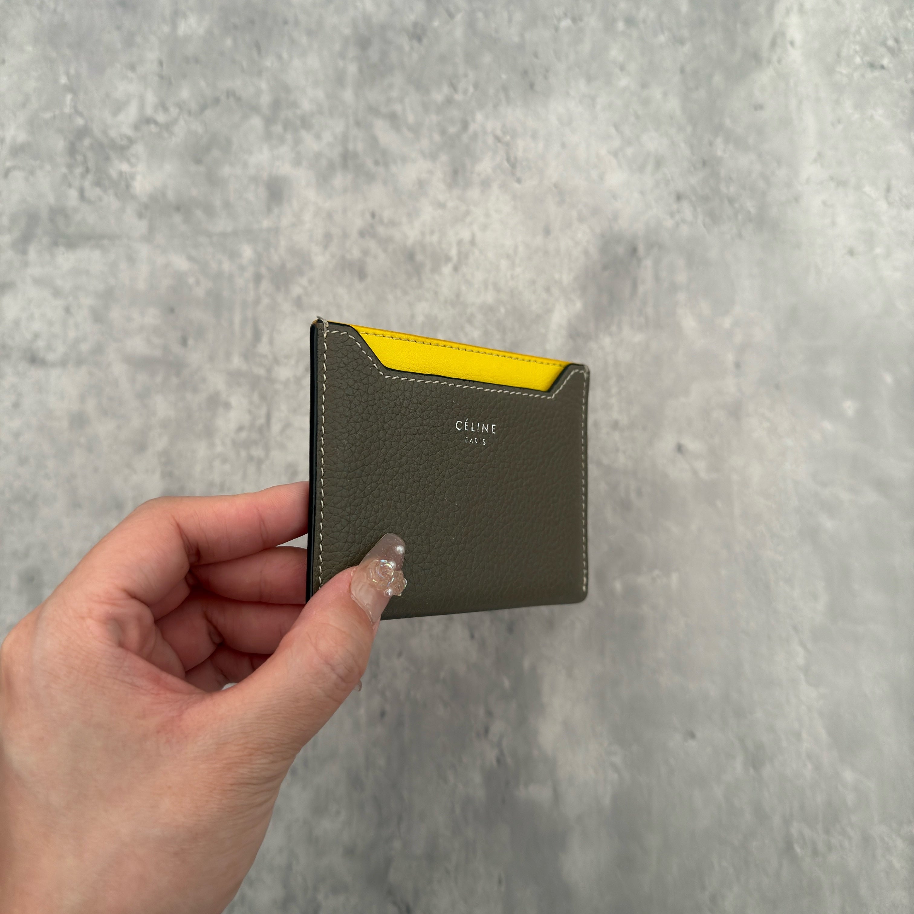 Celine Drummed Calfskin Bi-Color Cardholder in olive green and yellow, featuring a minimalist design with multiple card slots and central pocket.