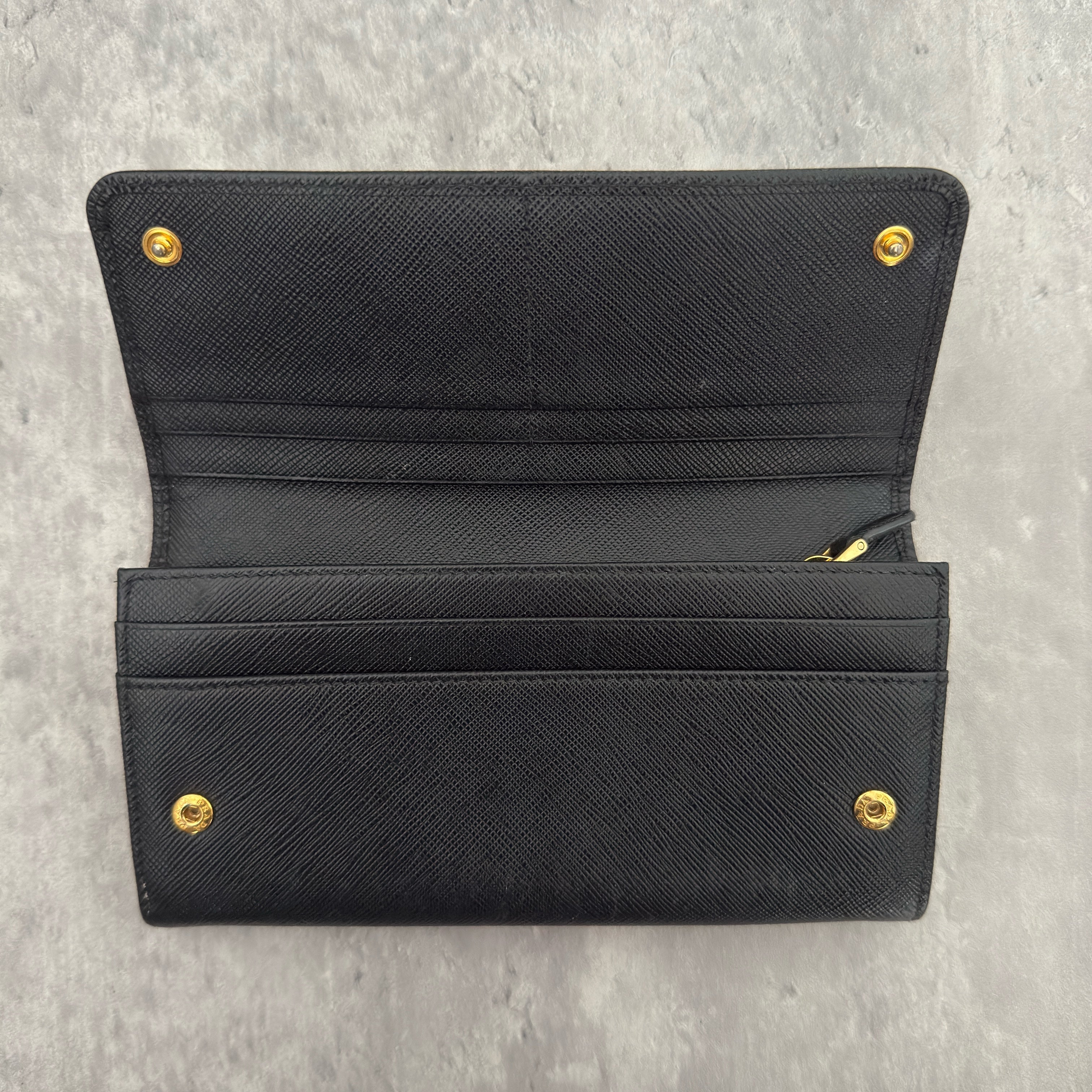 Prada Milano Black Saffiano Leather Ribbon Bow Long Wallet, crafted from textured black Saffiano leather with a gold-tone logo plaque and ribbon bow detail.