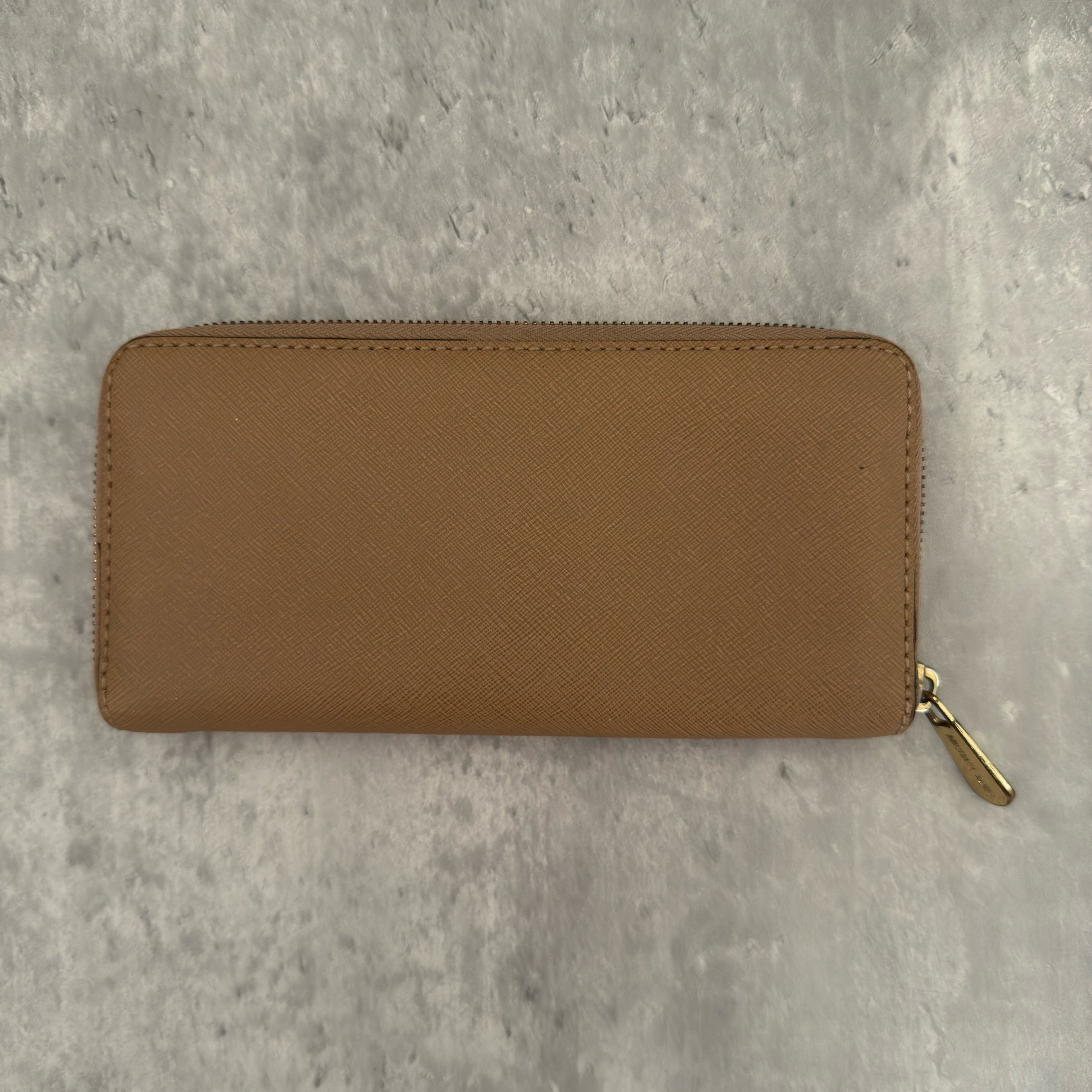 Michael Kors Jet Set Travel Zip-Around Saffiano Leather Continental Wallet in brown, featuring a gold-tone MK logo and zip-around closure.