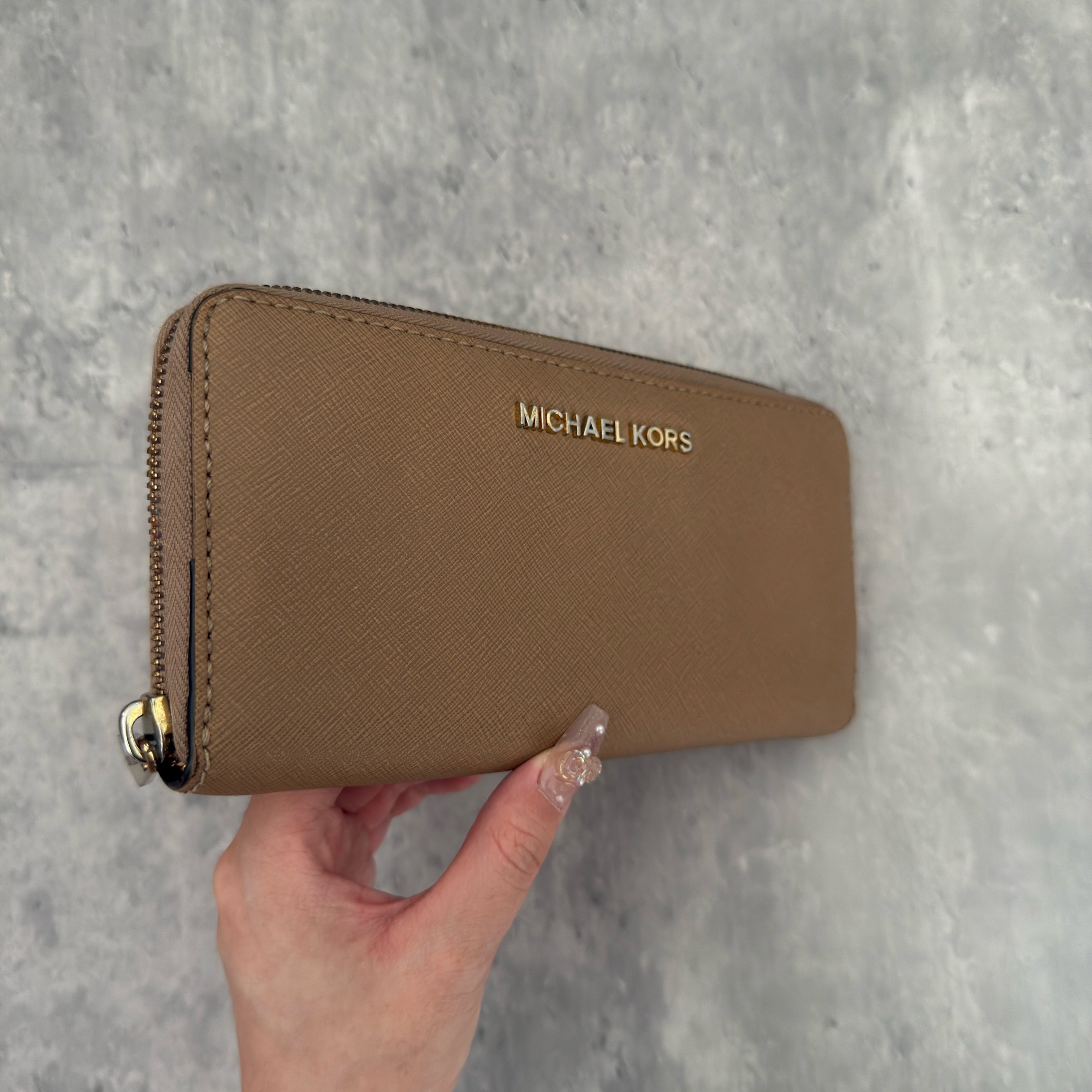 Michael Kors Jet Set Travel Zip-Around Saffiano Leather Continental Wallet in brown, featuring a gold-tone MK logo and zip-around closure.