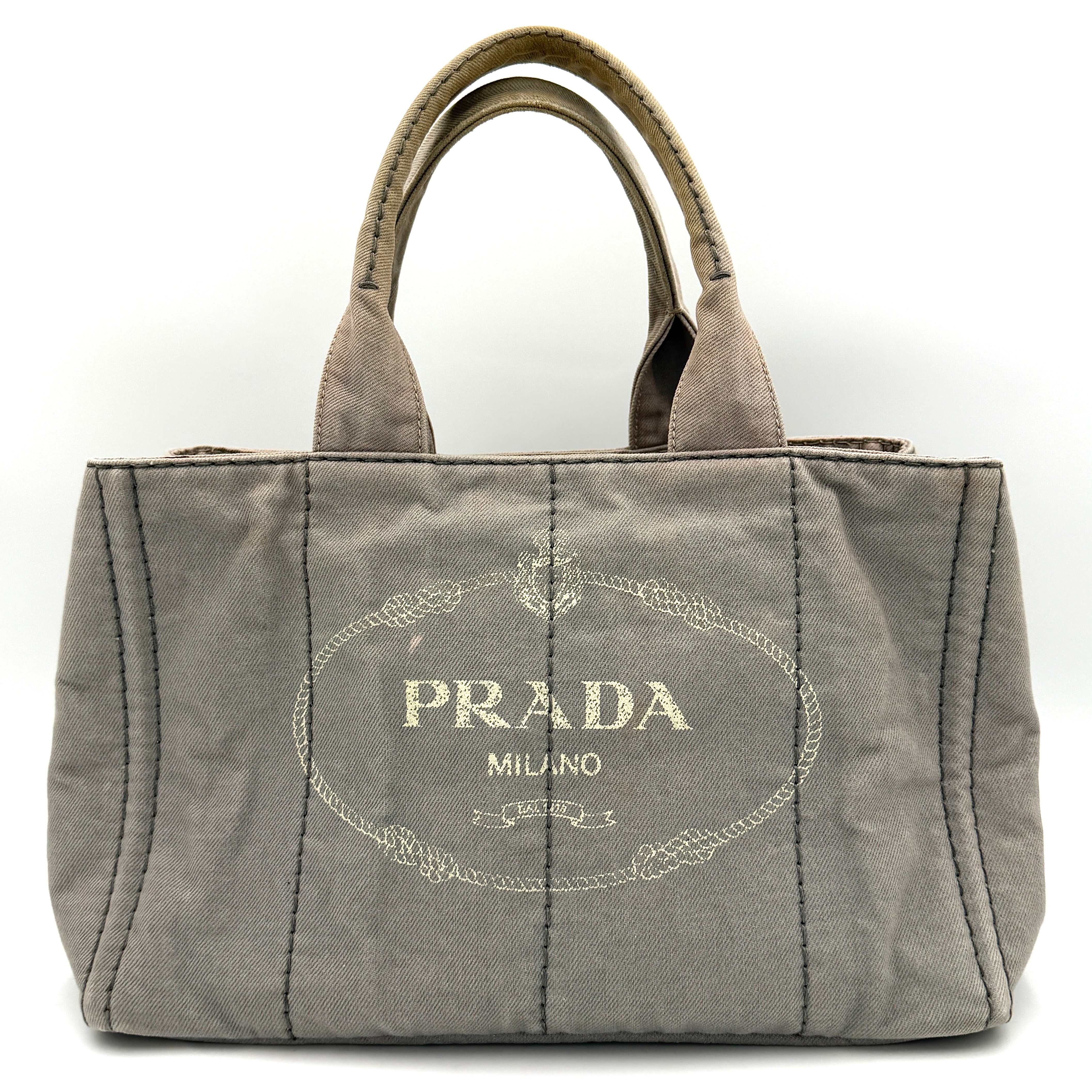 Prada Canapa Tote Bag in grey canvas with rope logo motif and dual top handles against a plain background.