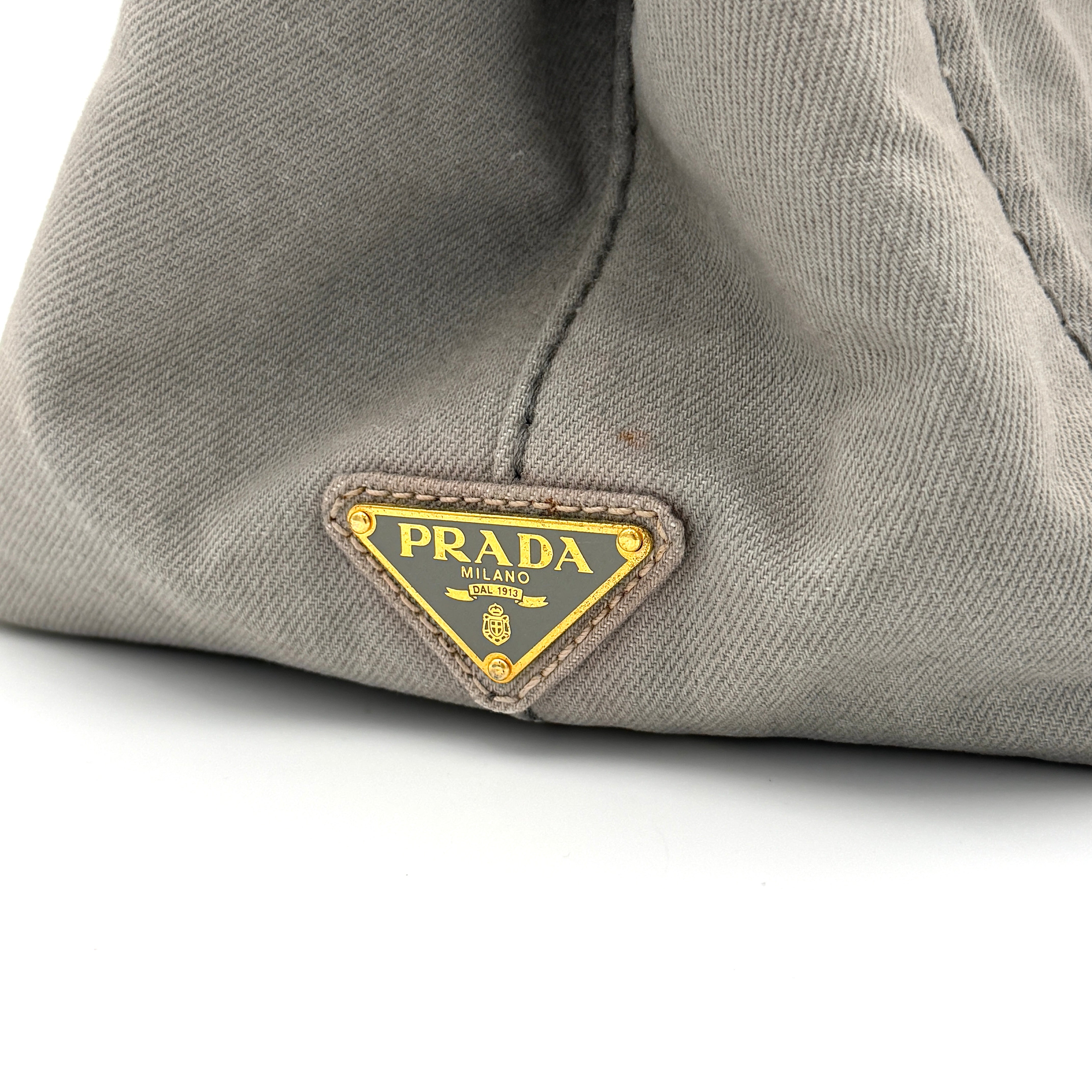 Prada Canapa Tote Bag in grey canvas with rope logo motif and dual top handles against a plain background.