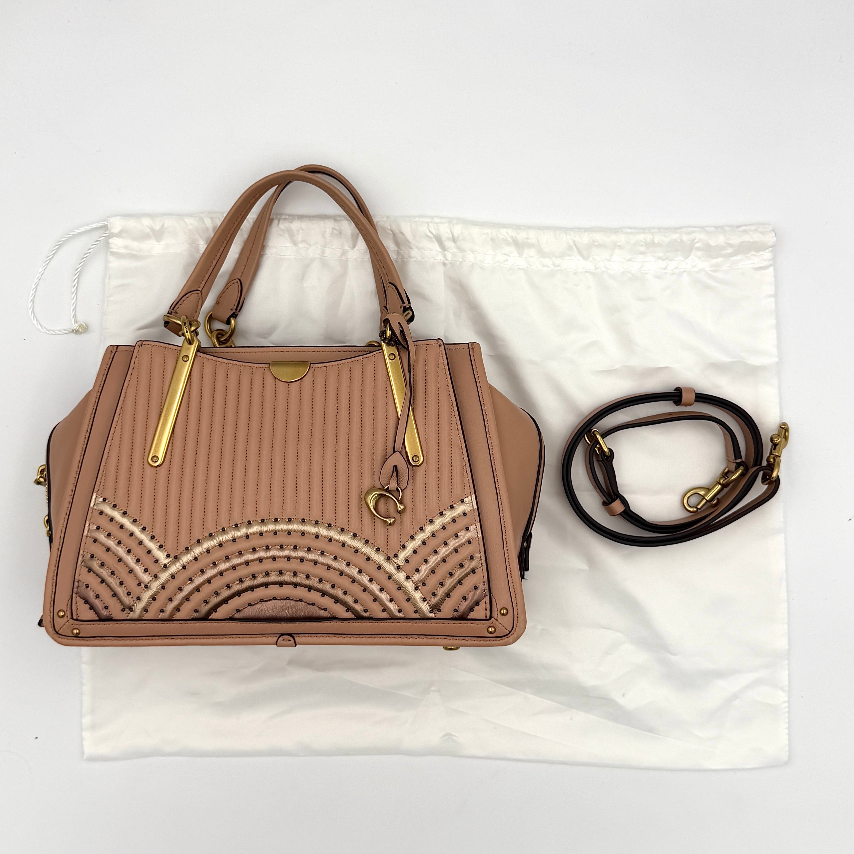 Coach Dreamer 27 handbag in nude pink leather with Deco quilting, gold rivets, and detachable strap, displayed elegantly on a plain background.