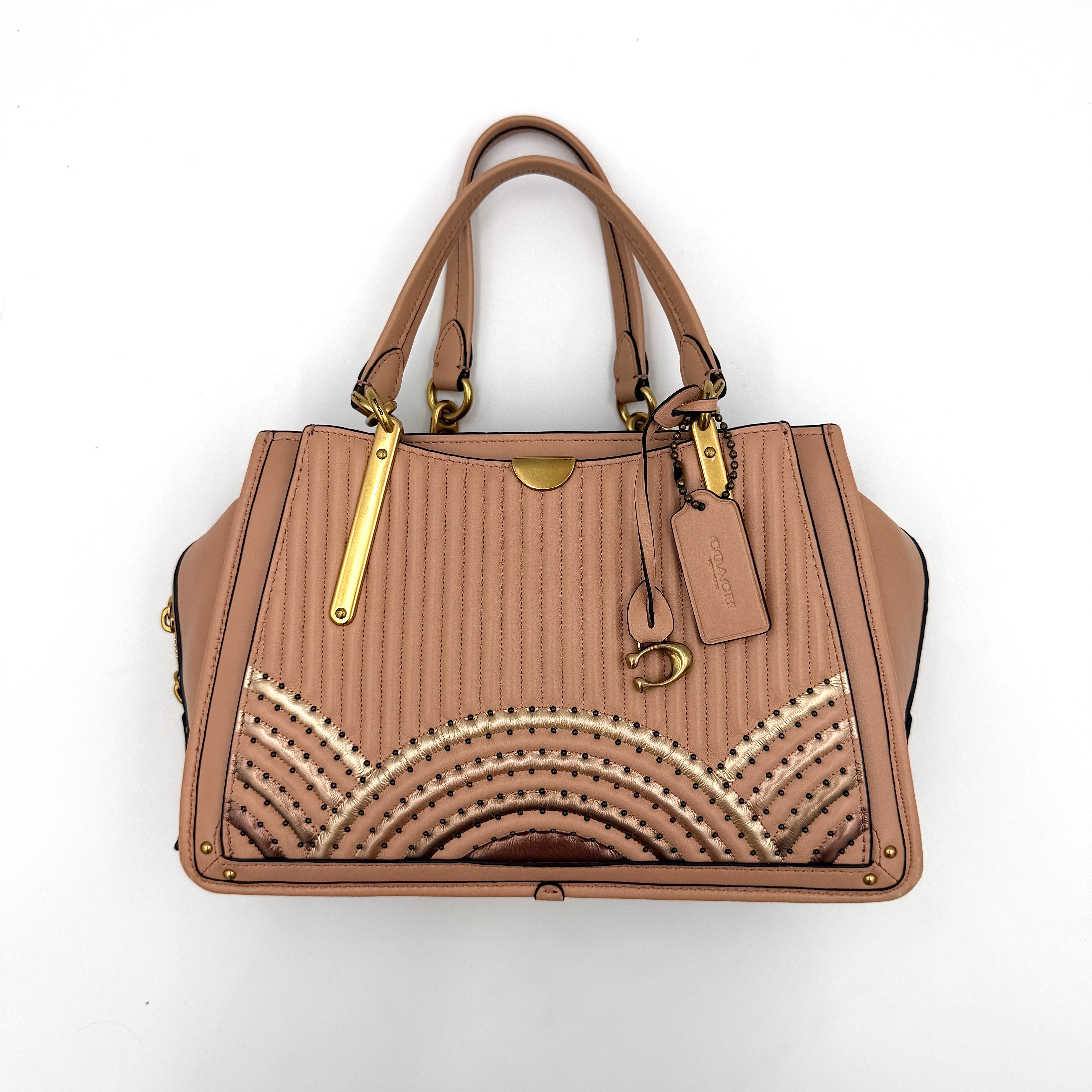 Coach Dreamer 27 handbag in nude pink leather with Deco quilting, gold rivets, and detachable strap, displayed elegantly on a plain background.