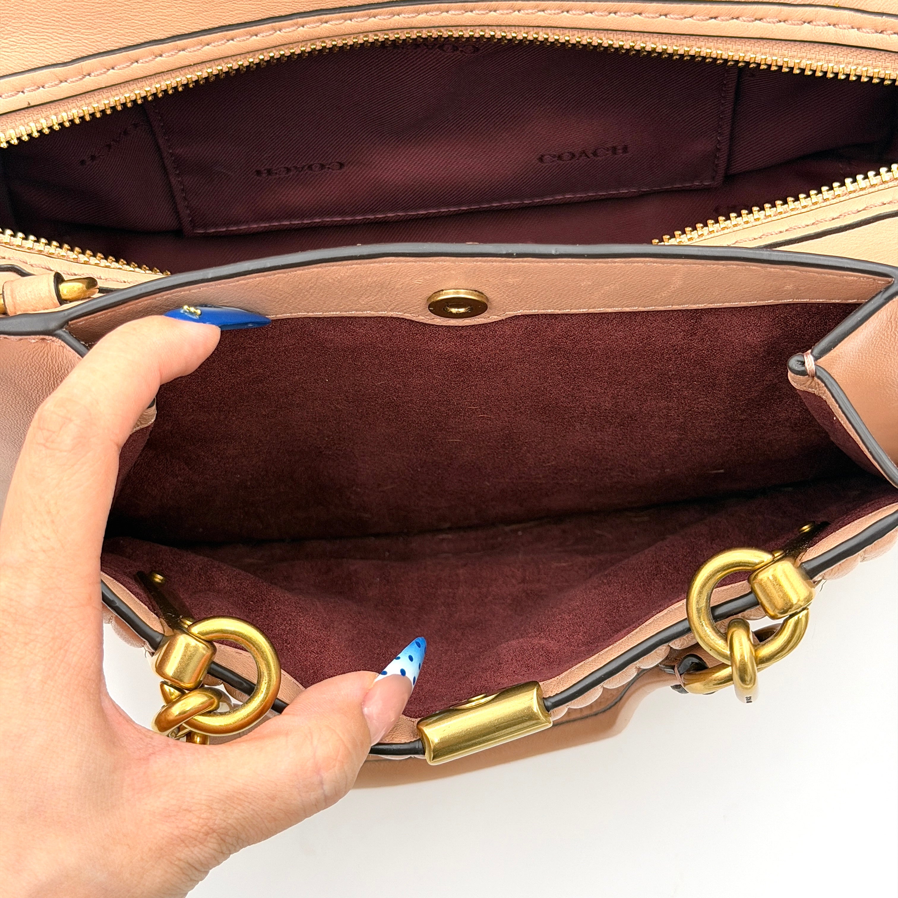 Coach Dreamer 27 handbag in nude pink leather with Deco quilting, gold rivets, and detachable strap, displayed elegantly on a plain background.