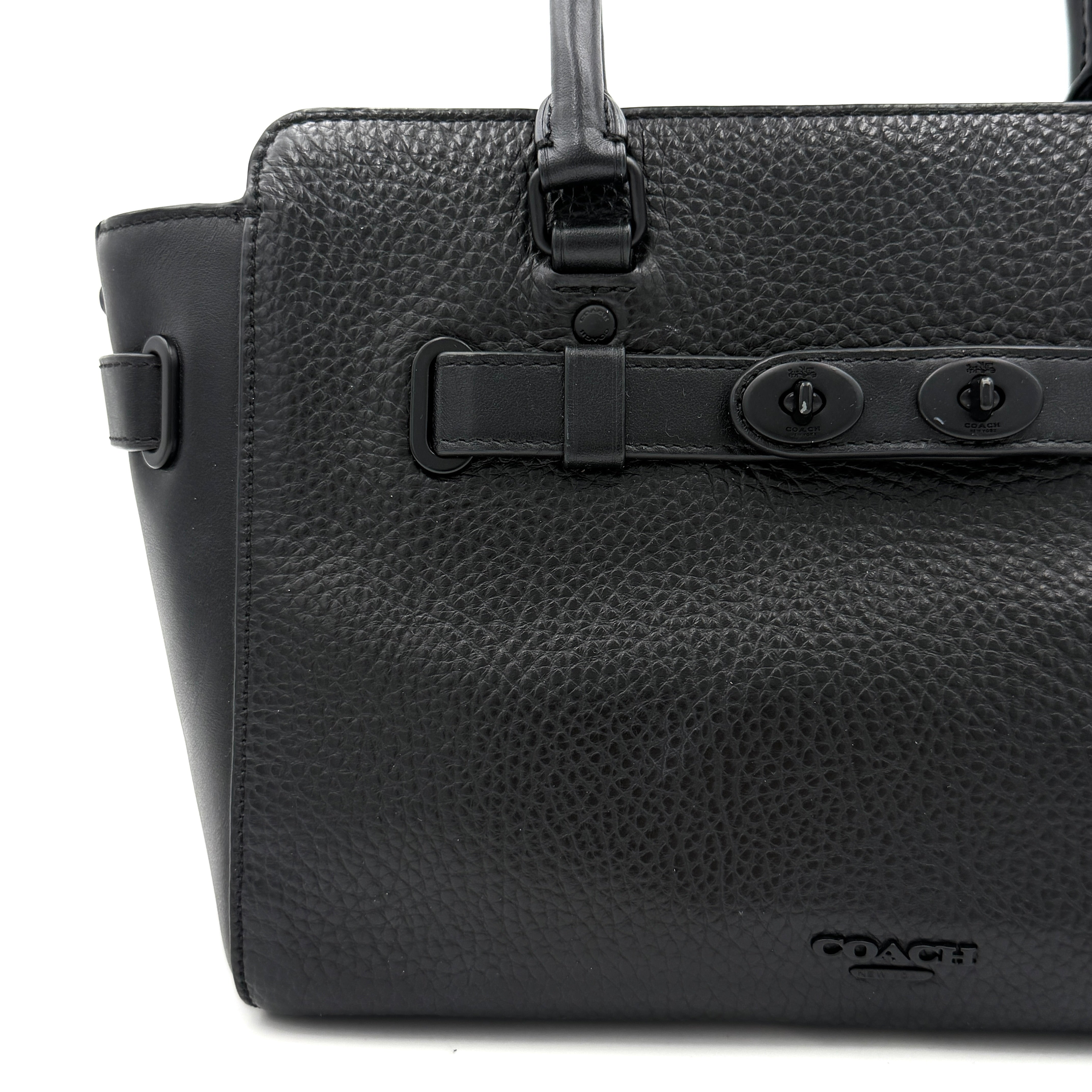 Coach Blake Carryall 25 bag in black pebbled leather with dual top handles, detachable strap, and front turnlock accents.