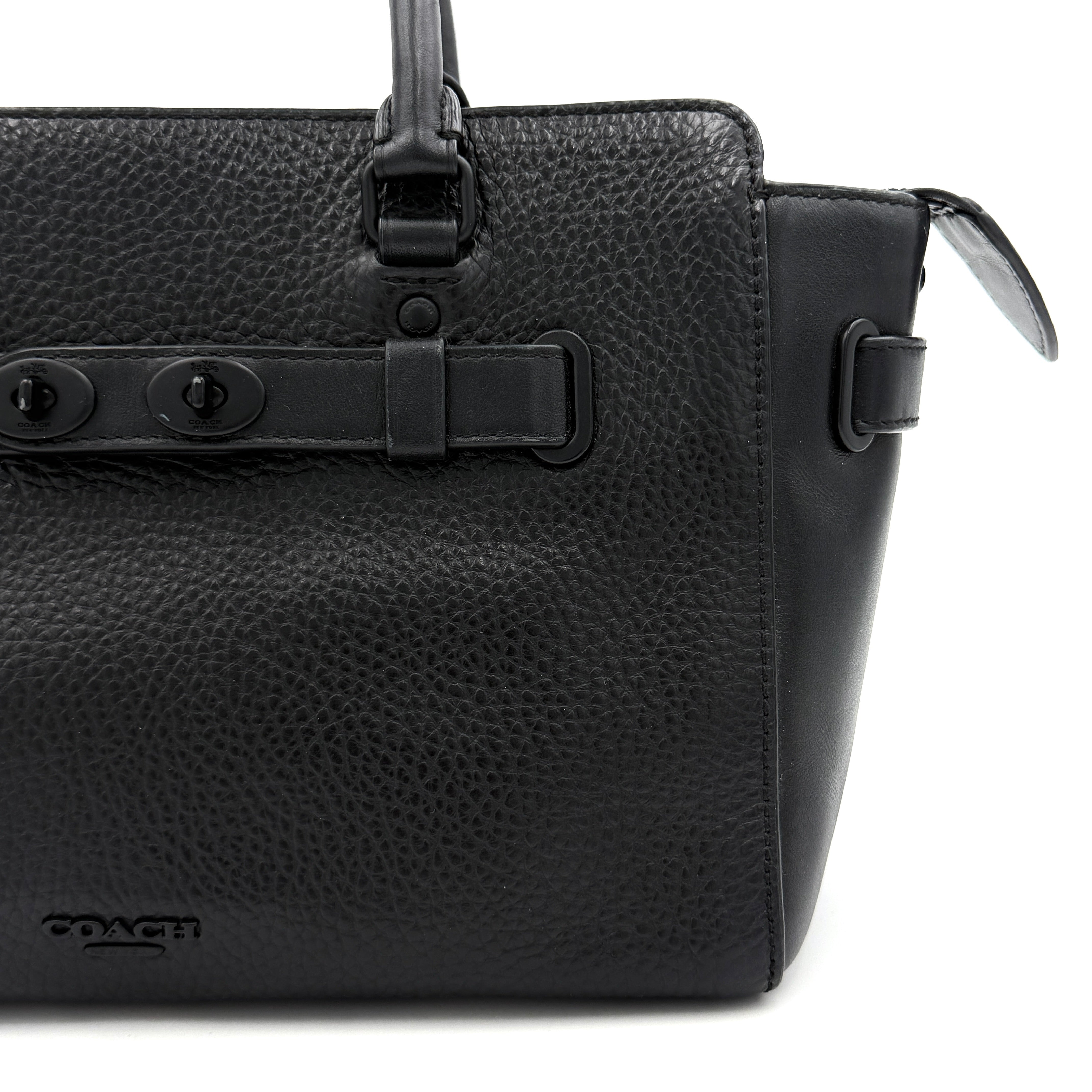 Coach Blake Carryall 25 bag in black pebbled leather with dual top handles, detachable strap, and front turnlock accents.