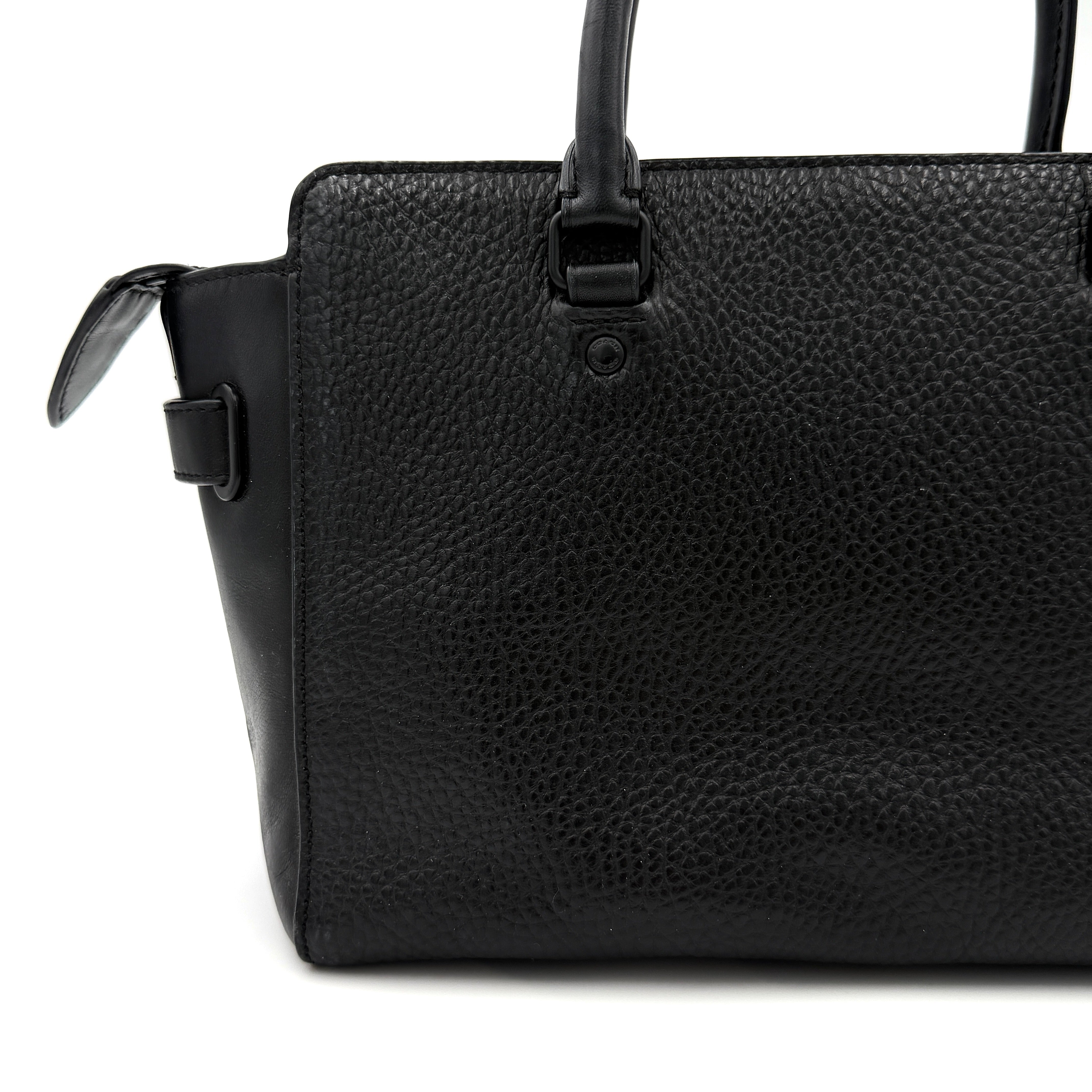 Coach Blake Carryall 25 bag in black pebbled leather with dual top handles, detachable strap, and front turnlock accents.