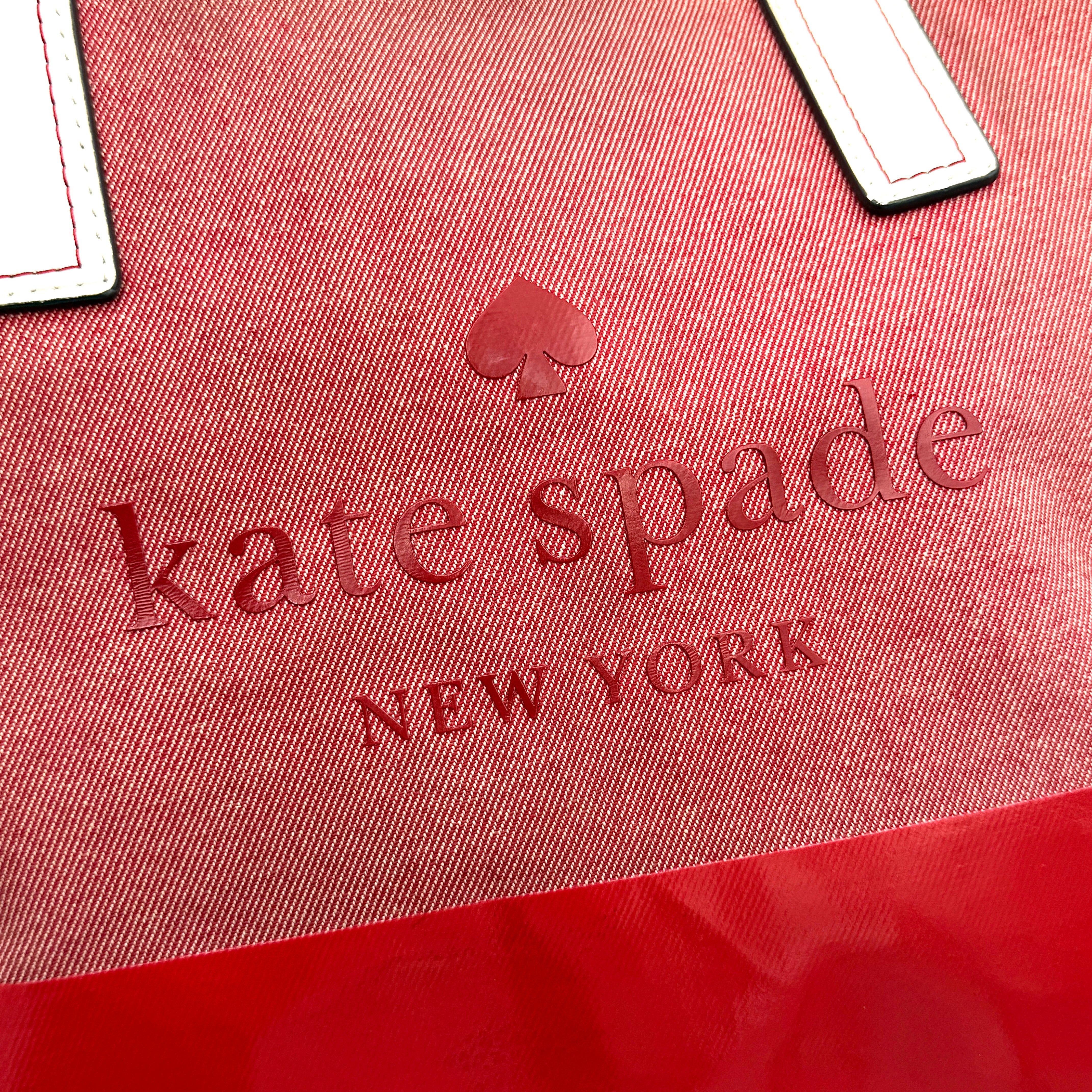 Kate Spade Ash Street Logo Tote in red canvas with glossy red leather base and ivory handles, shown against a white background.