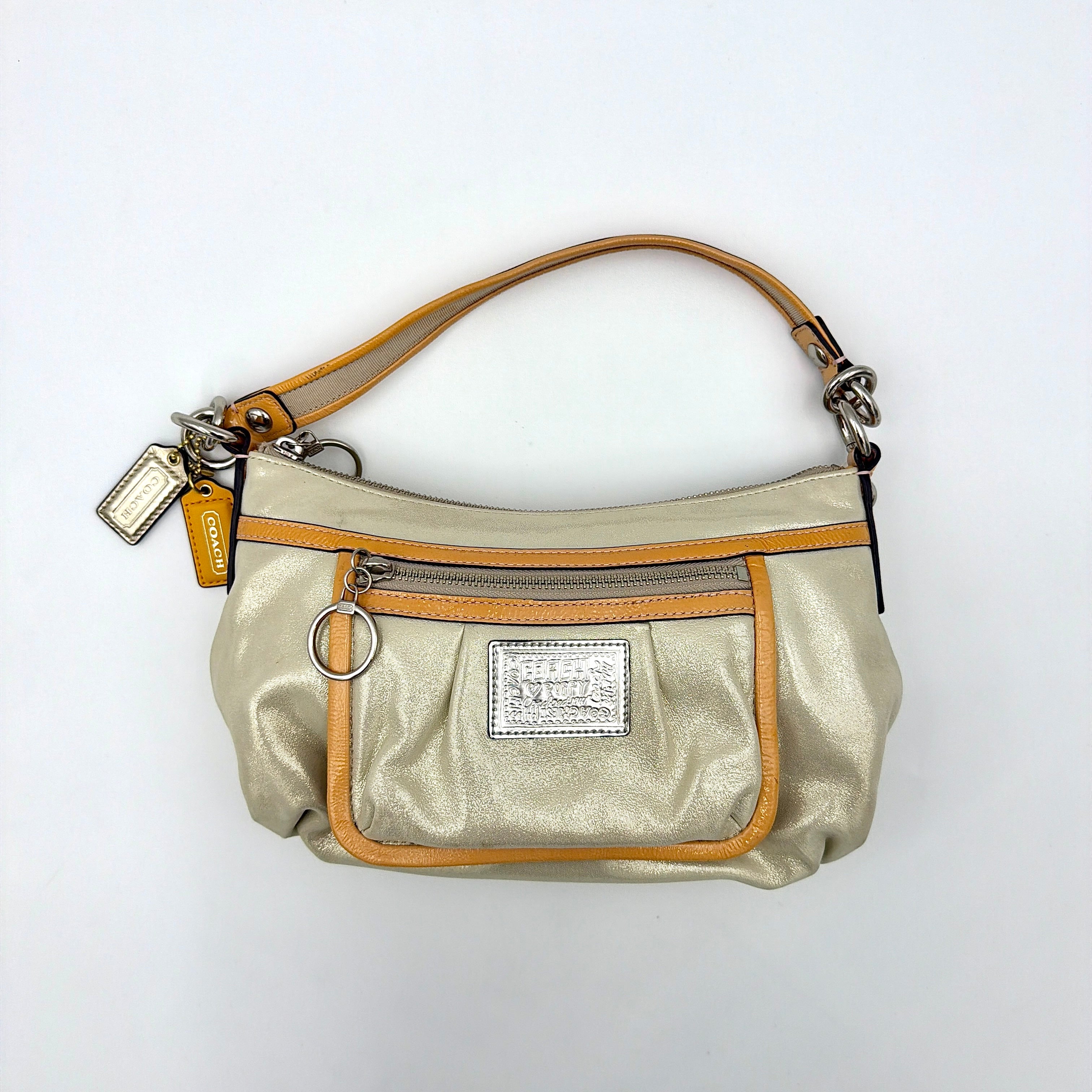 Coach Poppy Sparkle Groovy bag in cream with tan trim, metallic plaque, and detachable shoulder strap displayed alongside.